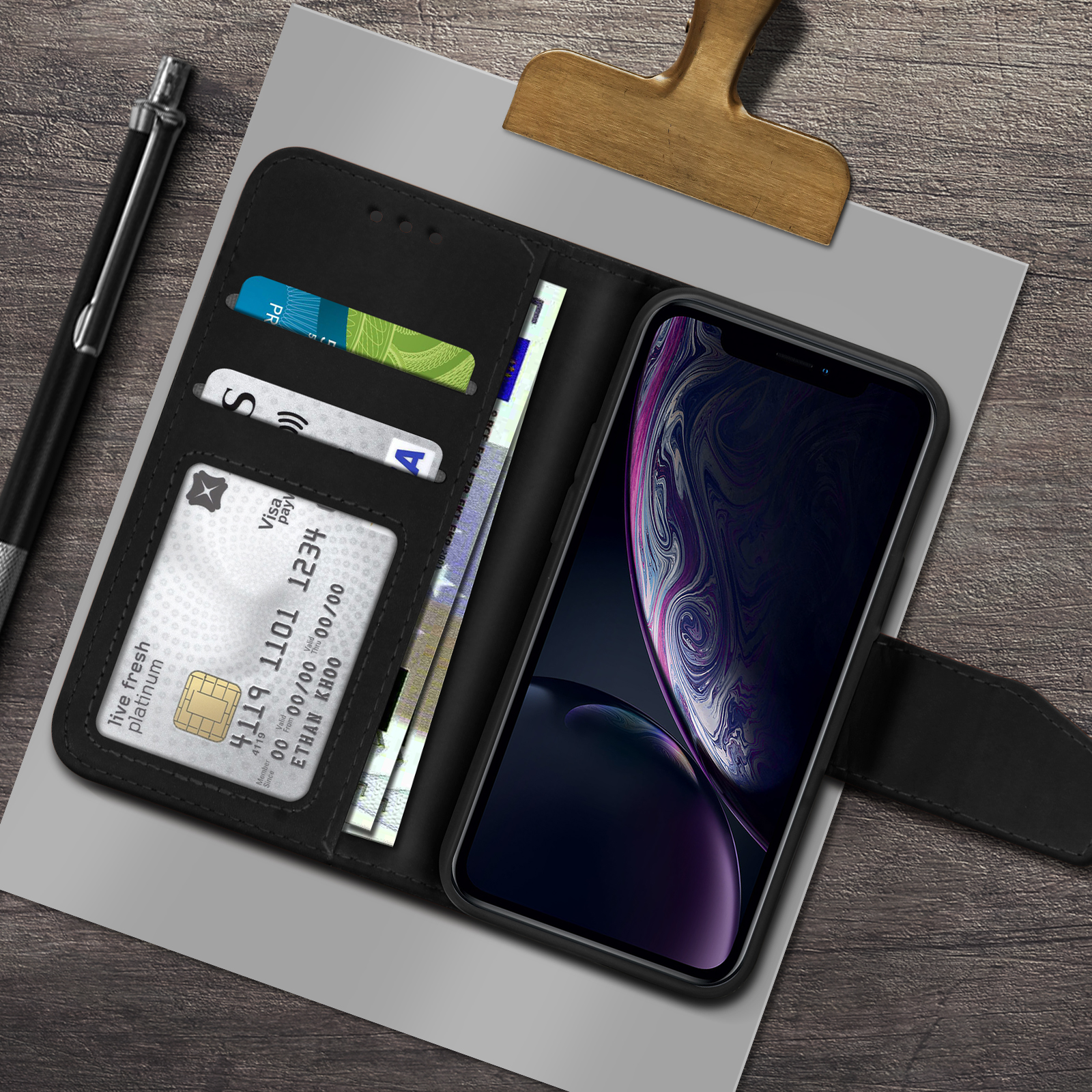 Custodia nera con telefono e carte all'interno, su sfondo in legno.