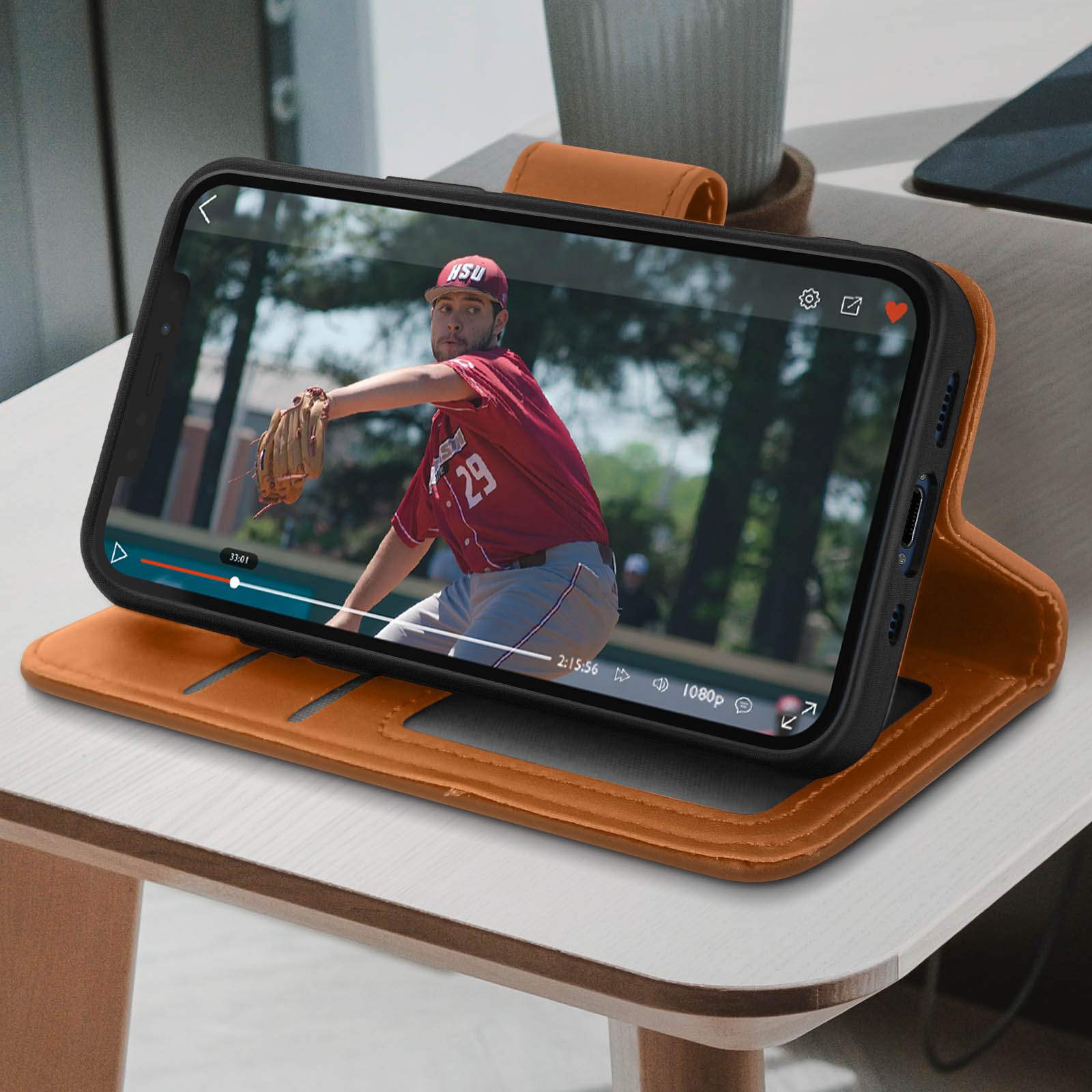 Un telefono in una custodia arancione sta riproducendo un video di un giocatore di baseball. Il telefono è su un tavolo di legno.