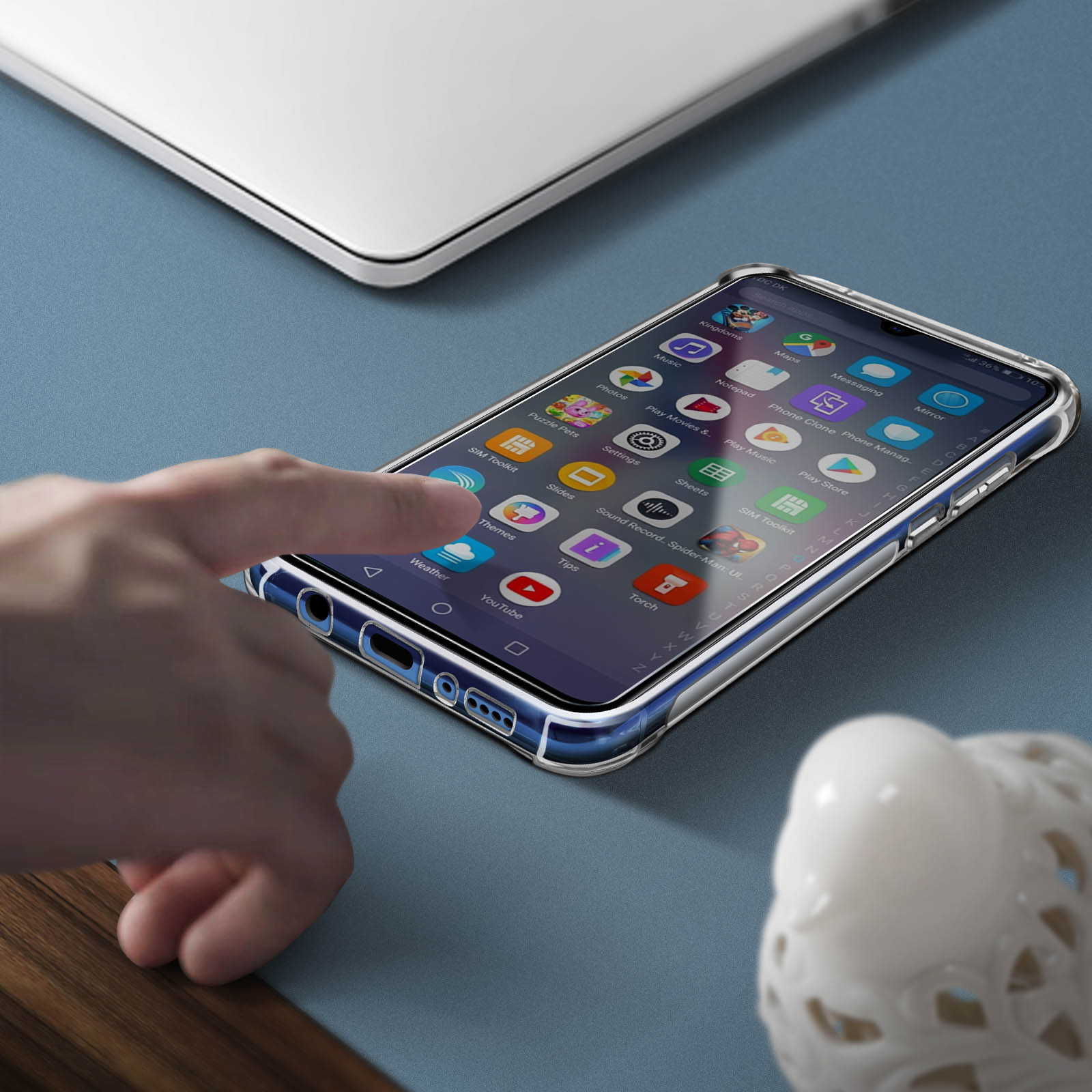 Telefono in una custodia trasparente su una superficie blu. Una mano lo raggiunge. Oggetto bianco sullo sfondo.