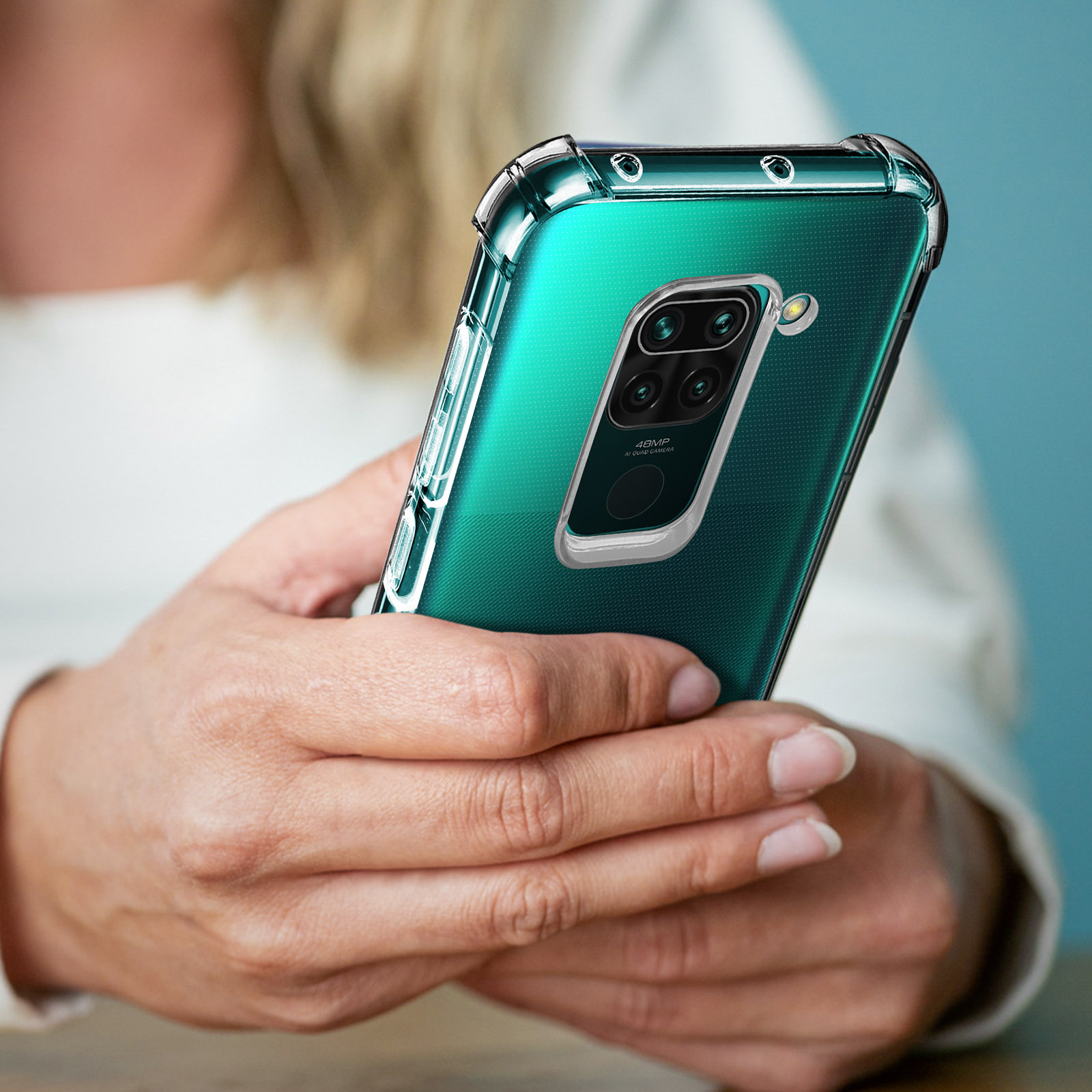 Una persona tiene in mano un telefono con custodia verde. Lo sfondo è sfocato.