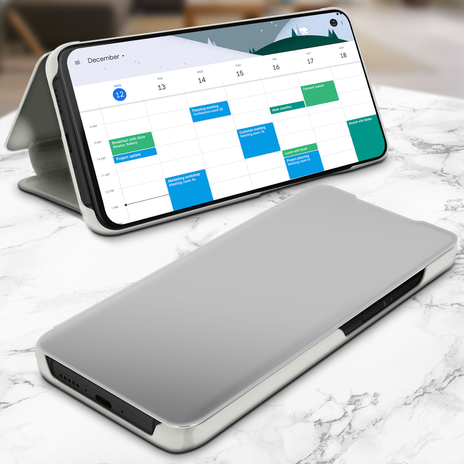 Un telefono in una custodia argentata con un calendario sullo schermo. Il telefono è aperto su una superficie di marmo.