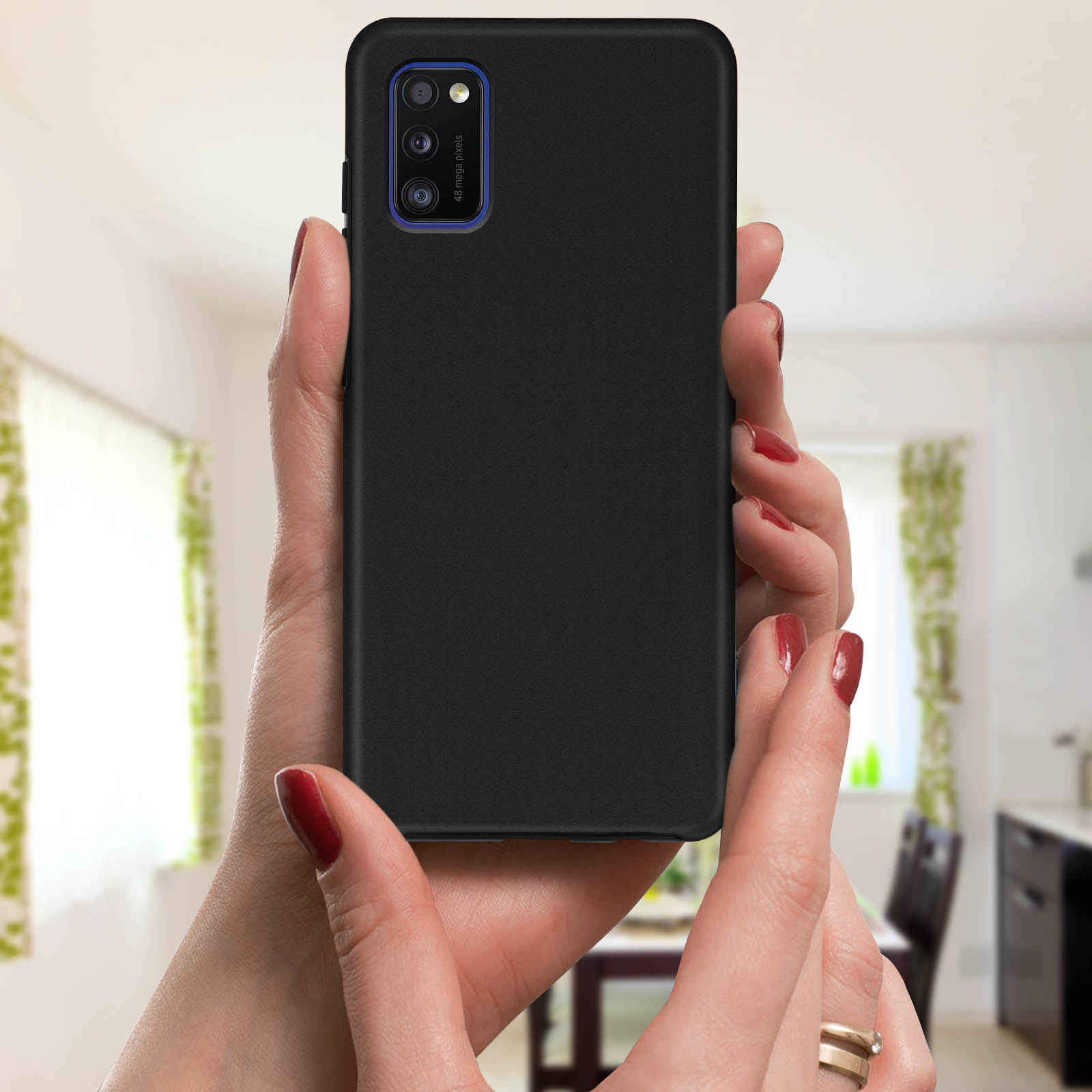 Une main tenant une coque de téléphone noire avec un boîtier de caméra bleu. L'arrière-plan est flou.