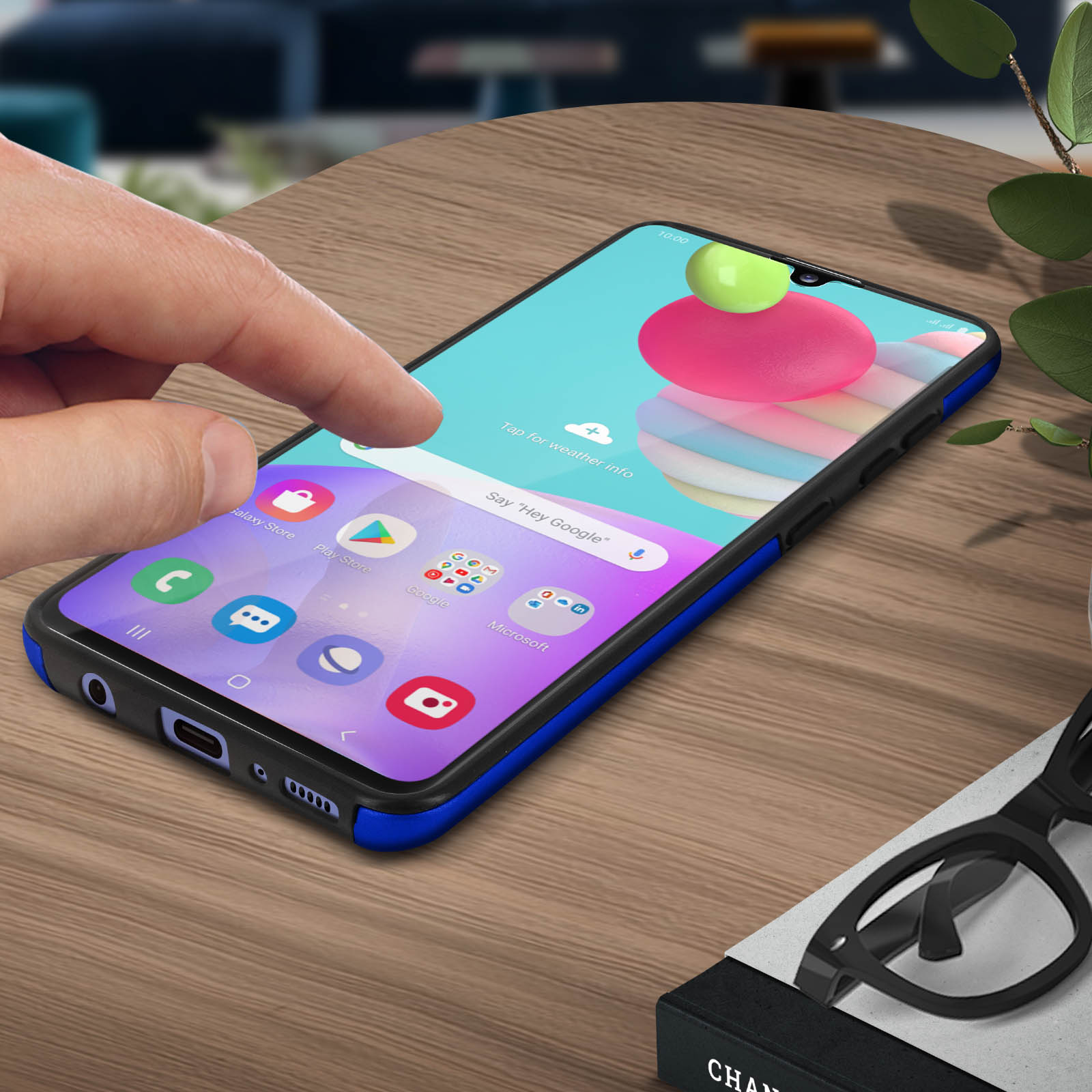 Dito che tocca lo schermo del telefono. Telefono in custodia blu su tavolo.
