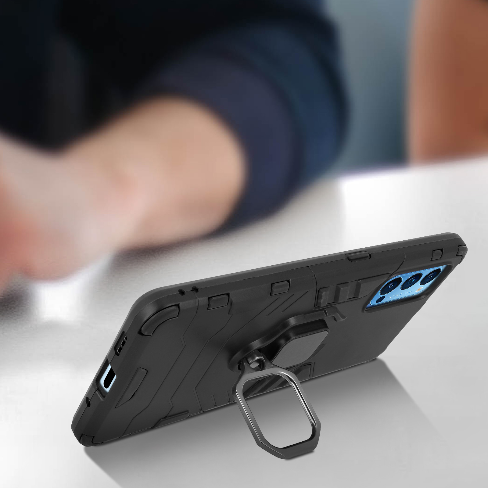 Coque de téléphone noire avec bague de support, en biais. Une table en fond.