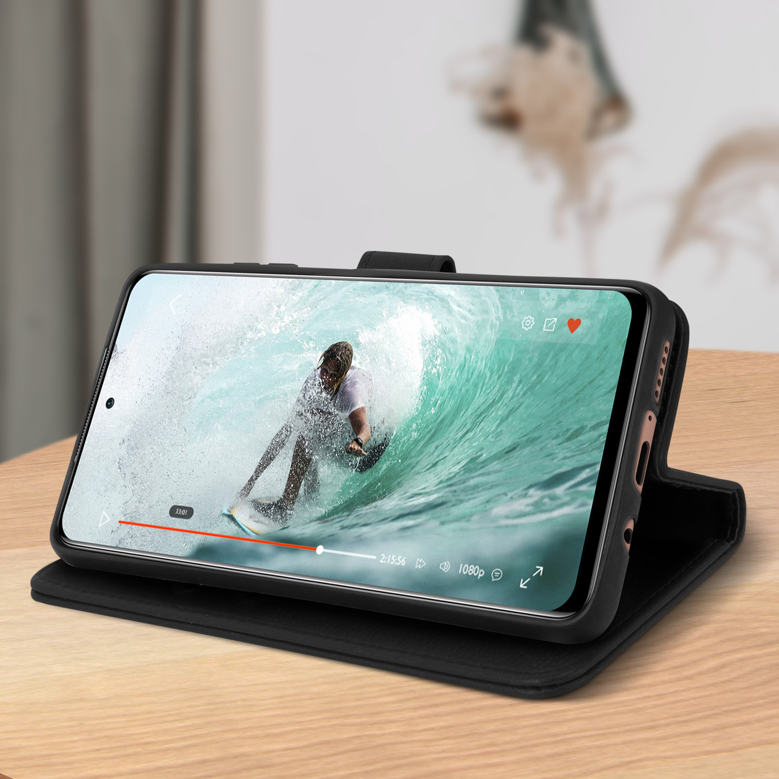 Coque de téléphone sur bois, montrant une vidéo d'un surfeur. La coque est noire.