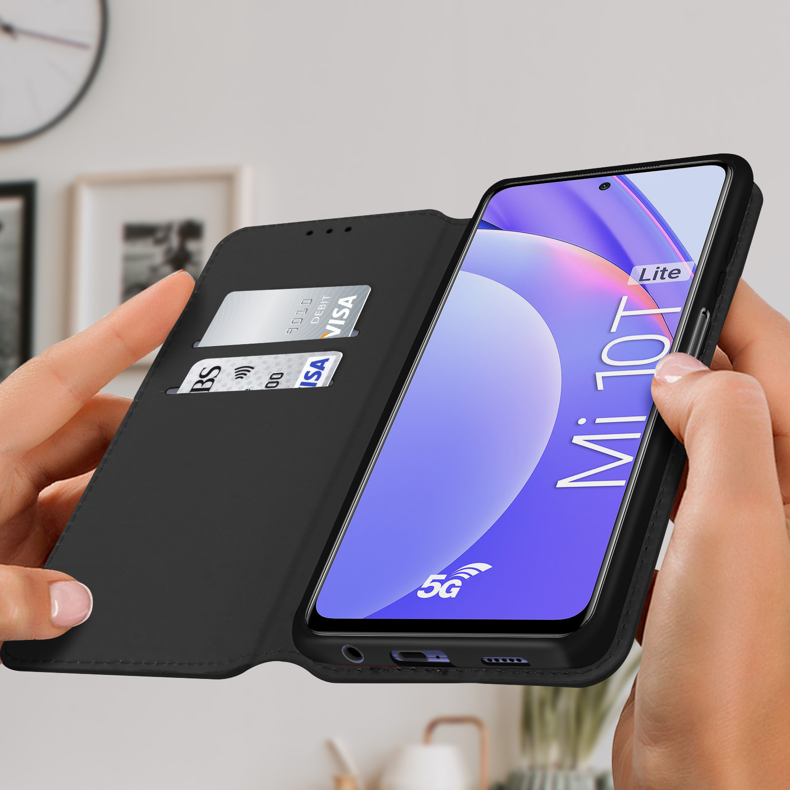 Mani che tengono un telefono in una custodia a portafoglio nera. All'interno una carta di credito. Schermo acceso.