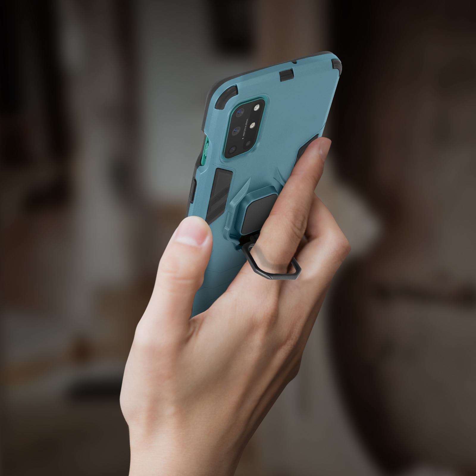 Una mano tiene in mano una custodia per telefono verde acqua. La custodia ha un anello nero sul retro.