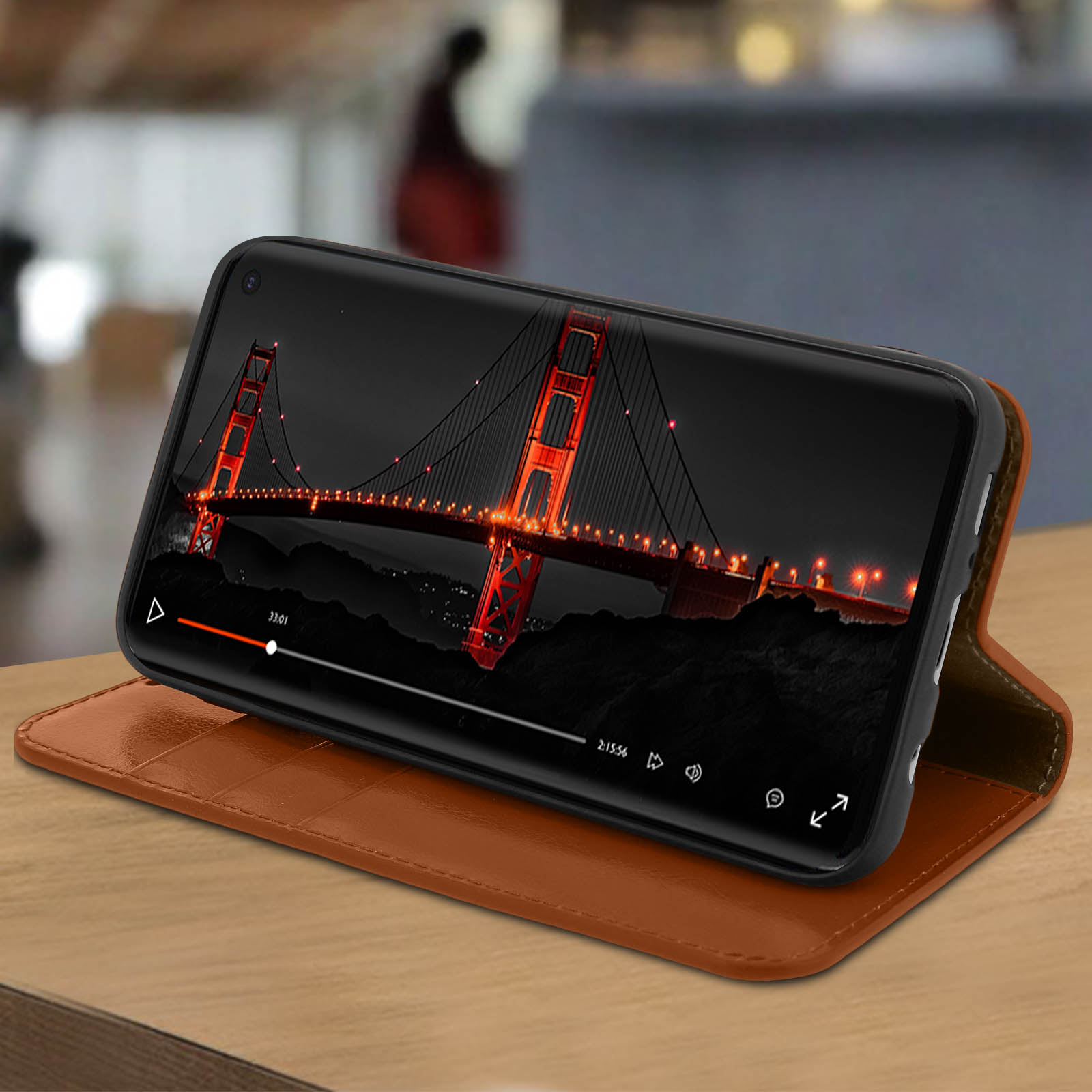 Telefono che mostra il video del Golden Gate Bridge. Custodia in pelle marrone su superficie di legno. Indicatore temporale.