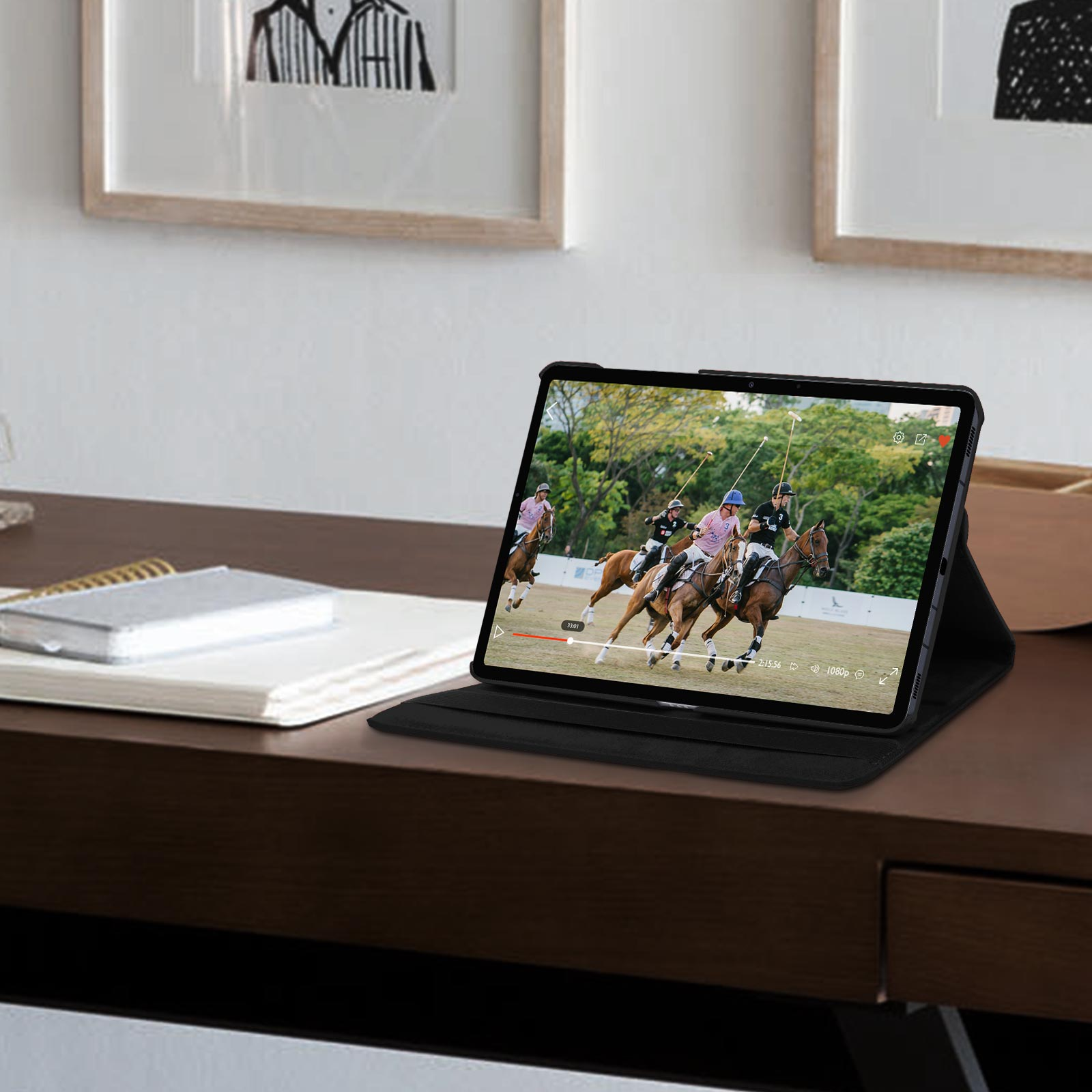 Tablet in custodia nera, mostra una partita di polo su una scrivania. Due quadri sullo sfondo.