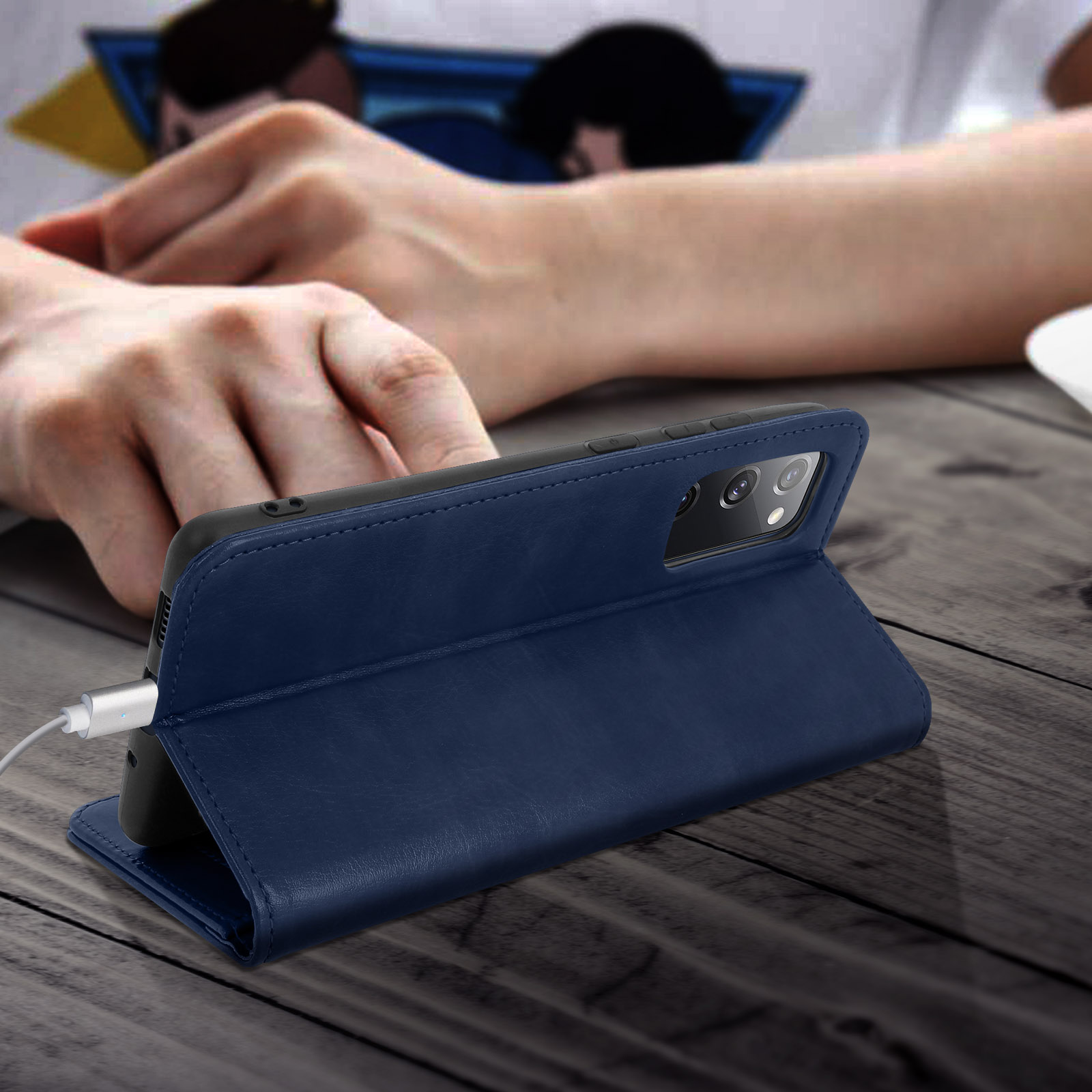 Een blauwe leren telefoonhoes met een telefoon erin, een witte kabel is aangesloten.