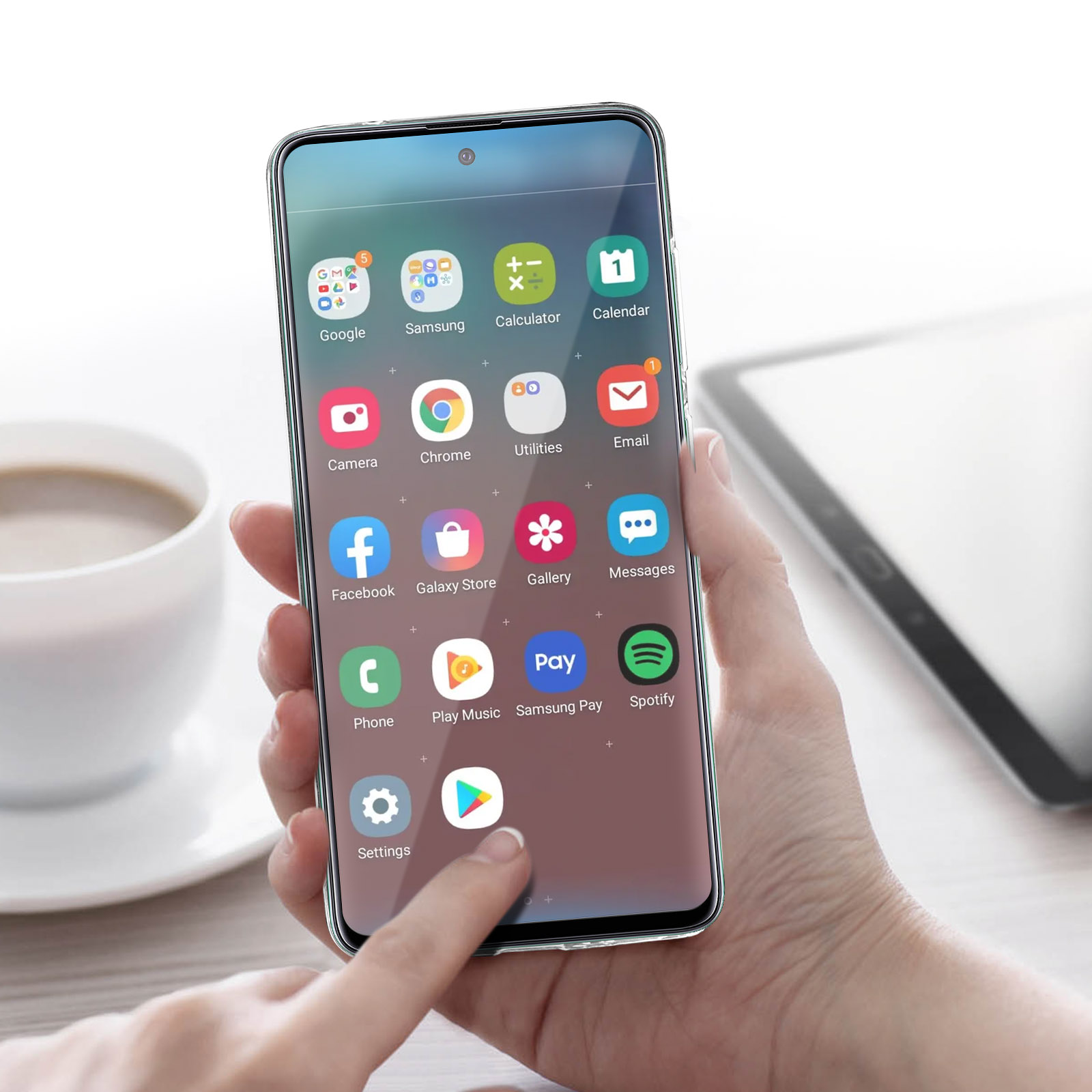 Hand hält Smartphone mit sichtbaren Apps. Kaffeetasse sichtbar. Ein zweites Telefon oder Tablet im Hintergrund.