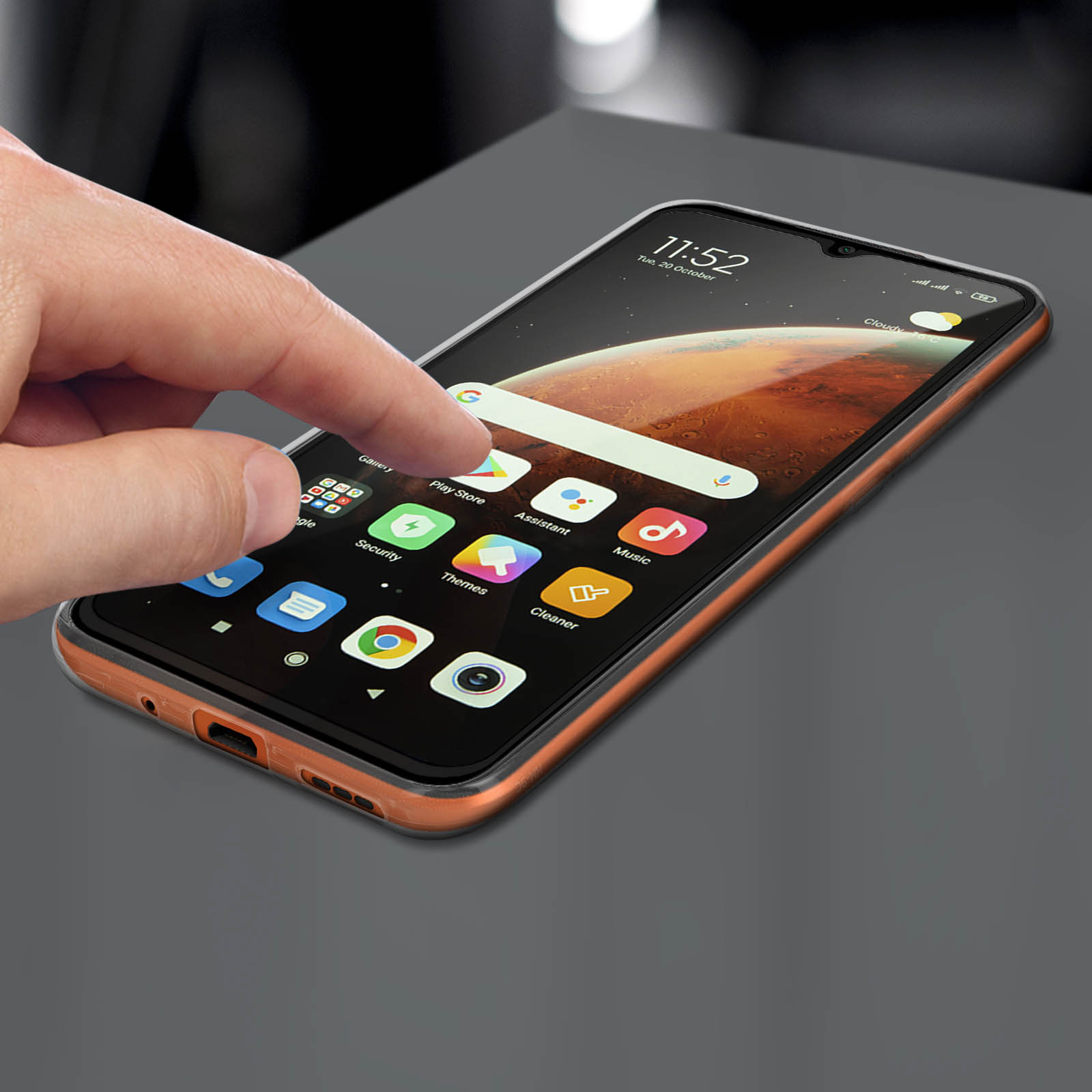 Una mano tocca lo schermo di un telefono che mostra icone di app. Il telefono ha bordi arancioni e sfondo scuro.
