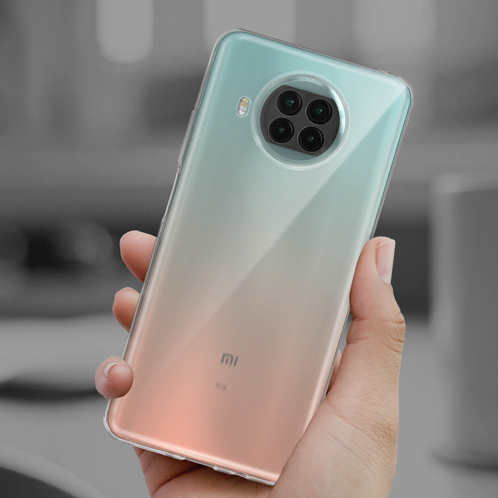 Mano che tiene uno smartphone con una custodia trasparente. Il telefono ha un retro sfumato. Xiaomi 5G.