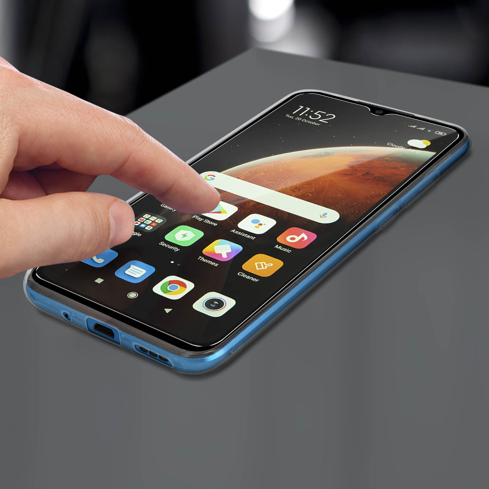 Mano che tocca lo schermo di un telefono con icone di app. Il telefono è su una superficie grigio scuro.