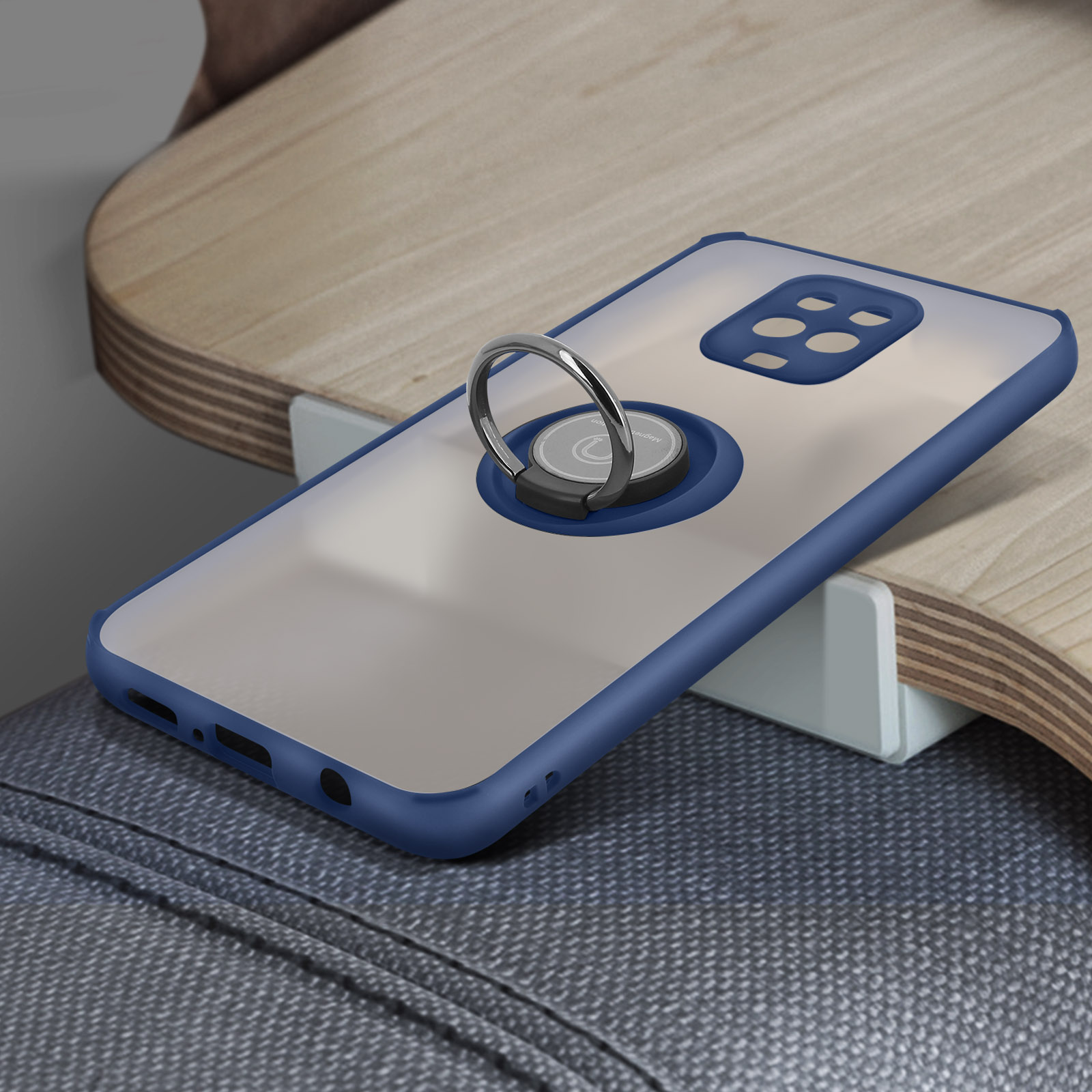 Téléphone dans un étui à bord bleu avec un support d'anneau. Le téléphone est sur une surface en bois. En dessous, un jean gris.