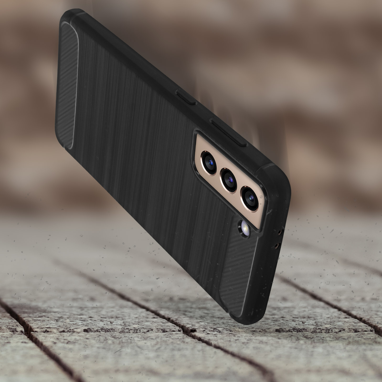 Custodia nera per telefono con un telefono all'interno che cade su una superficie di legno. La custodia è strutturata.