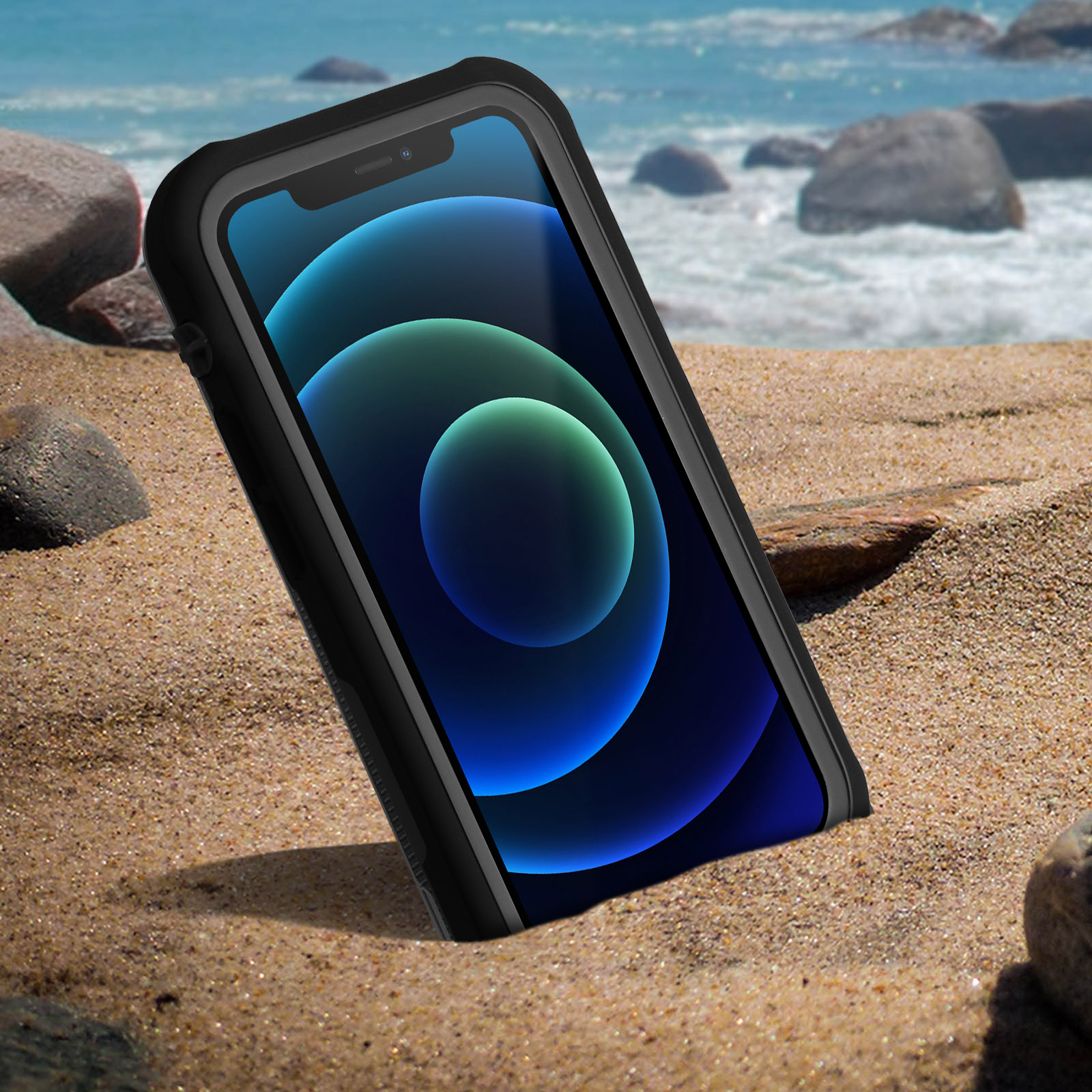 Un telefono in una custodia nera su una spiaggia sabbiosa con l'oceano sullo sfondo.