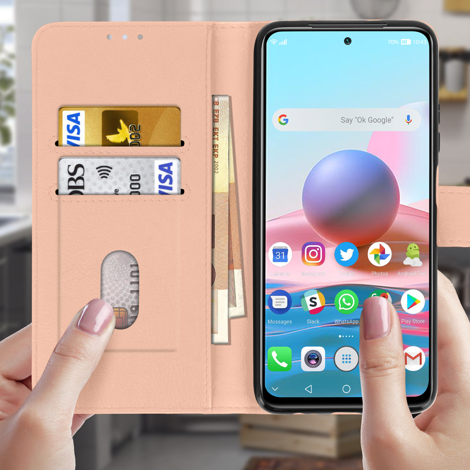 Ein Telefon in einem rosa Etui mit Karten und Geld. Eine Hand hält das Telefon und zeigt den Startbildschirm.