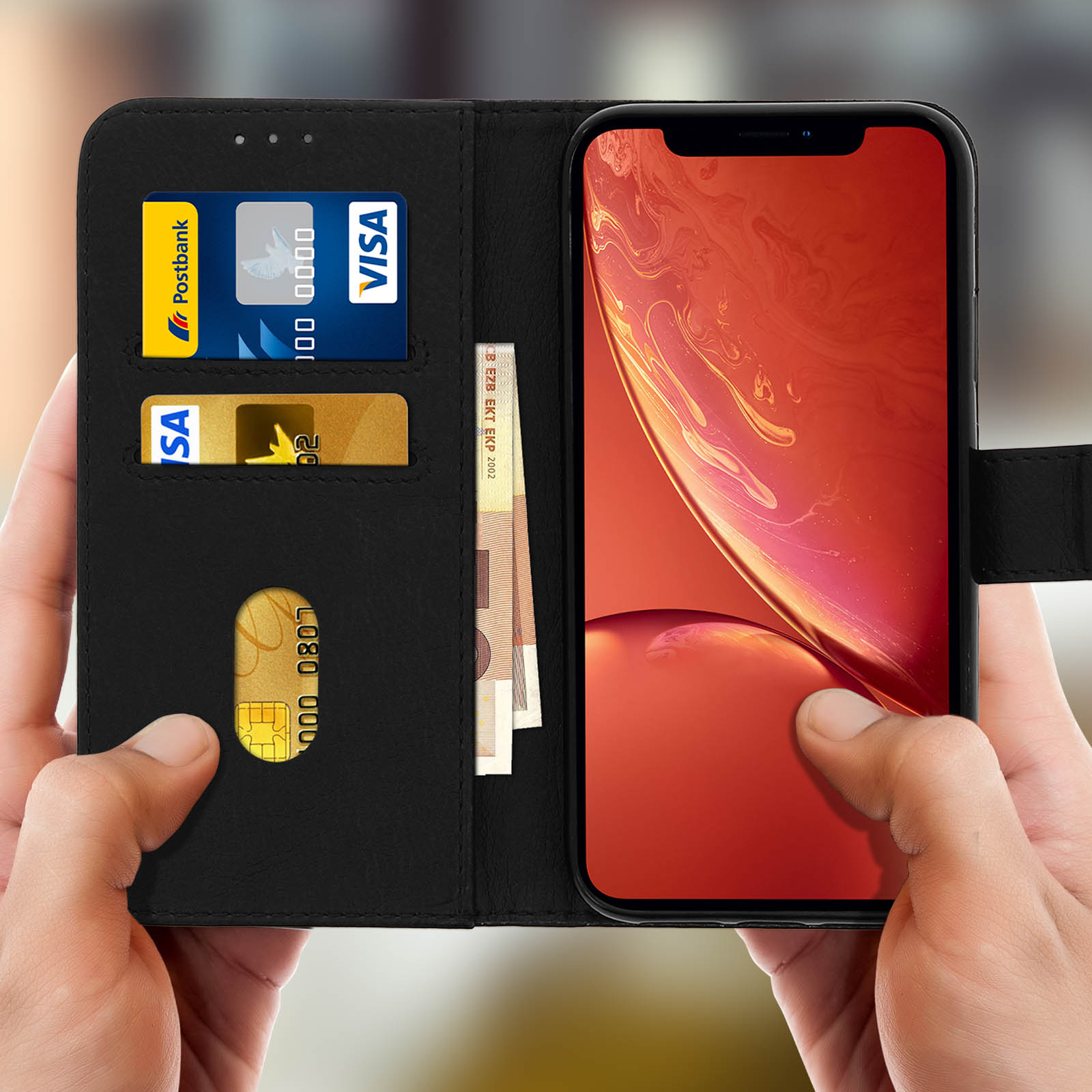 Mani che tengono una custodia per telefono nera con carte e denaro.