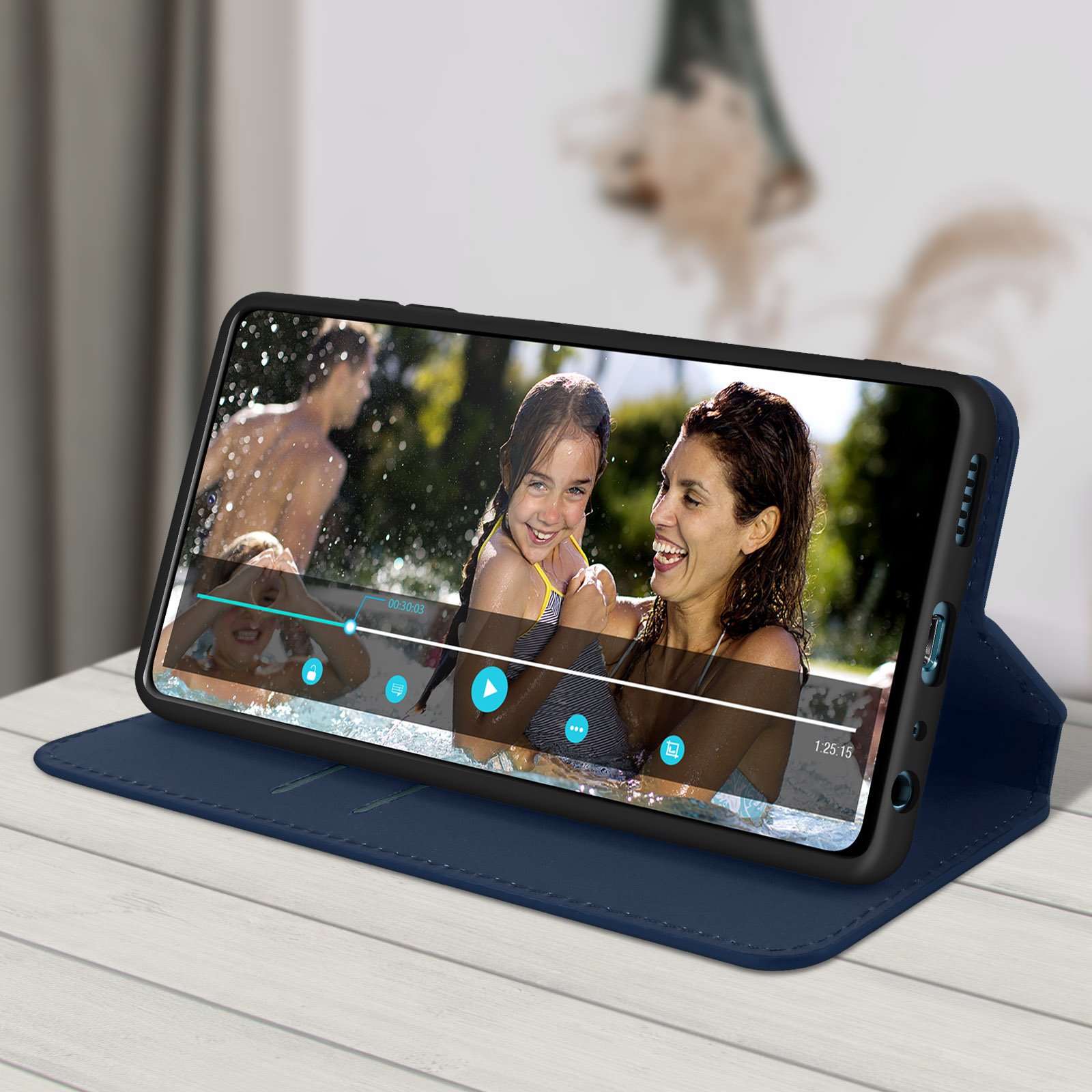 Un telefono in una custodia blu che mostra un video di una famiglia in piscina. La custodia è aperta.