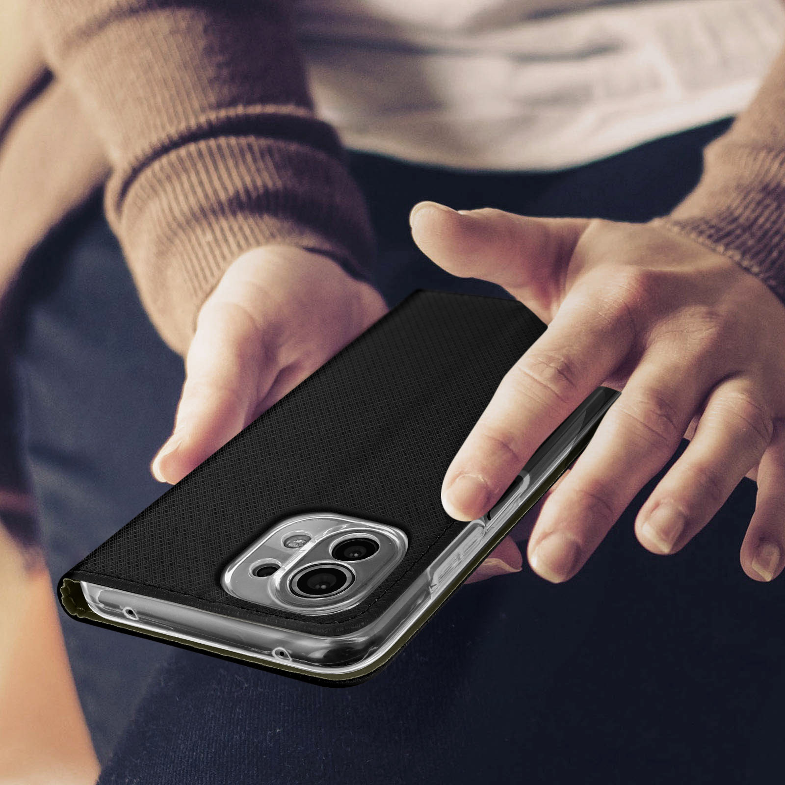 Personne tenant un téléphone dans un étui noir. L'étui a une surface texturée.
