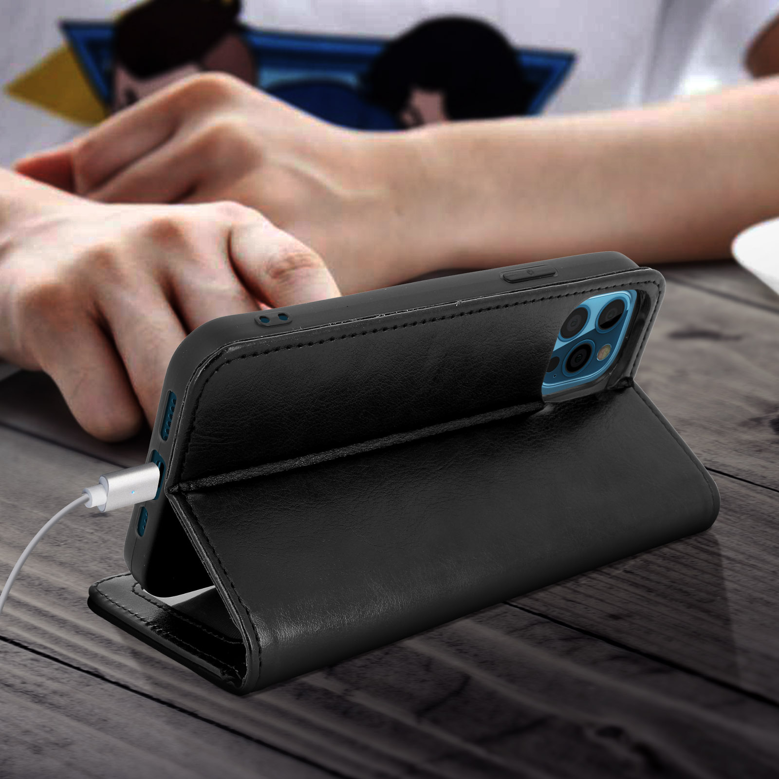 Un étui de téléphone en cuir noir avec un téléphone à l'intérieur, connecté à un câble de chargement.