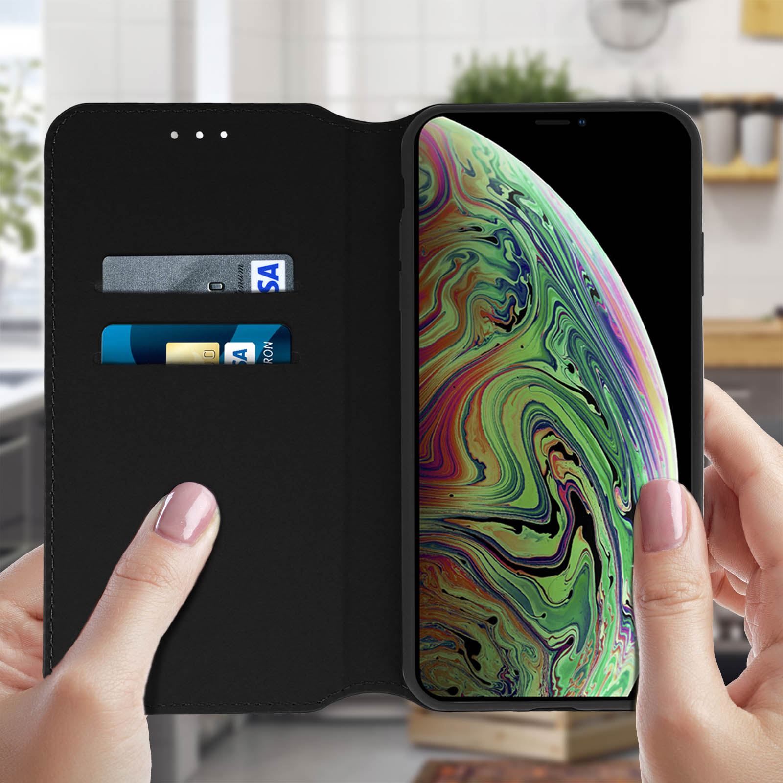 Mani che tengono una custodia nera. Telefono con schermo acceso. Due carte nella custodia.