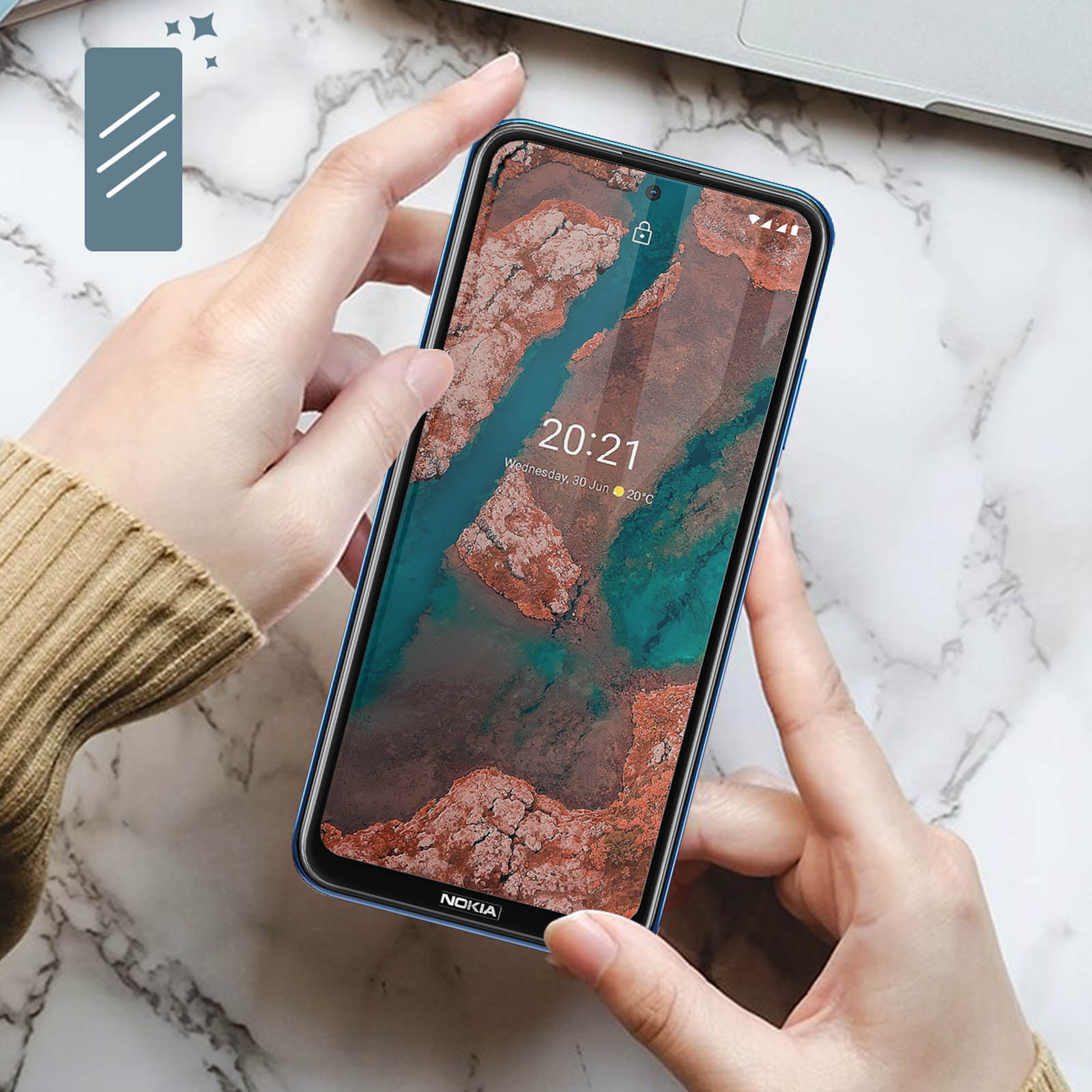 Mani che tengono un telefono Nokia blu. Il telefono mostra un'immagine del paesaggio e l'ora. Superficie di marmo sullo sfondo.