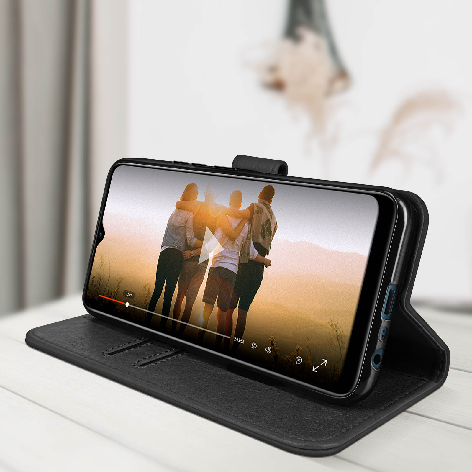 Un telefono in una custodia che mostra un video di persone, aperto, su un tavolo.