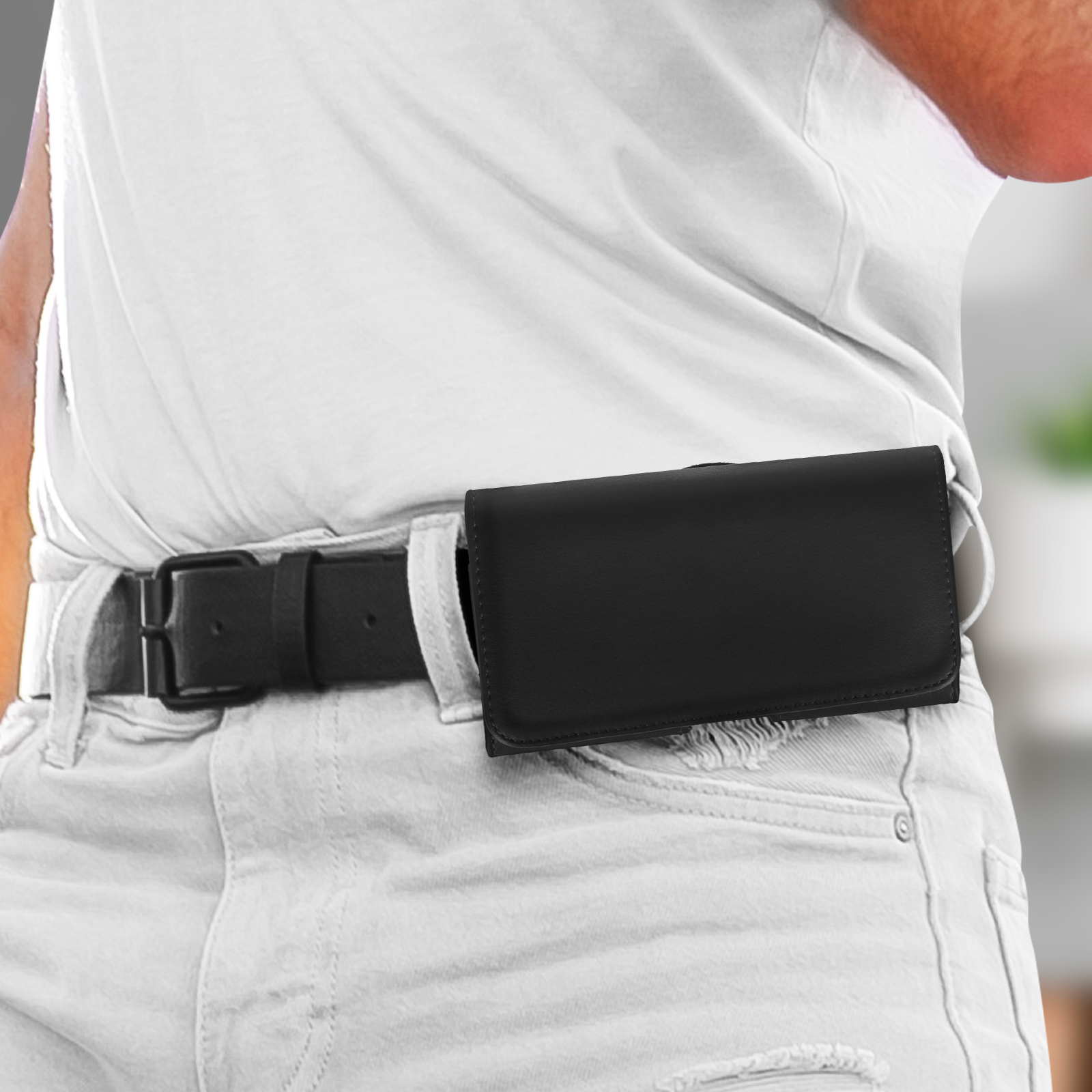 Una persona indossa una camicia bianca e jeans, una custodia nera per telefono sulla cintura.