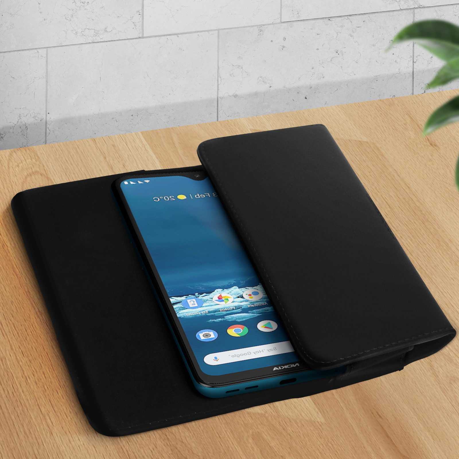 Un telefono nero in una custodia nera, con schermo visibile, su una superficie di legno.