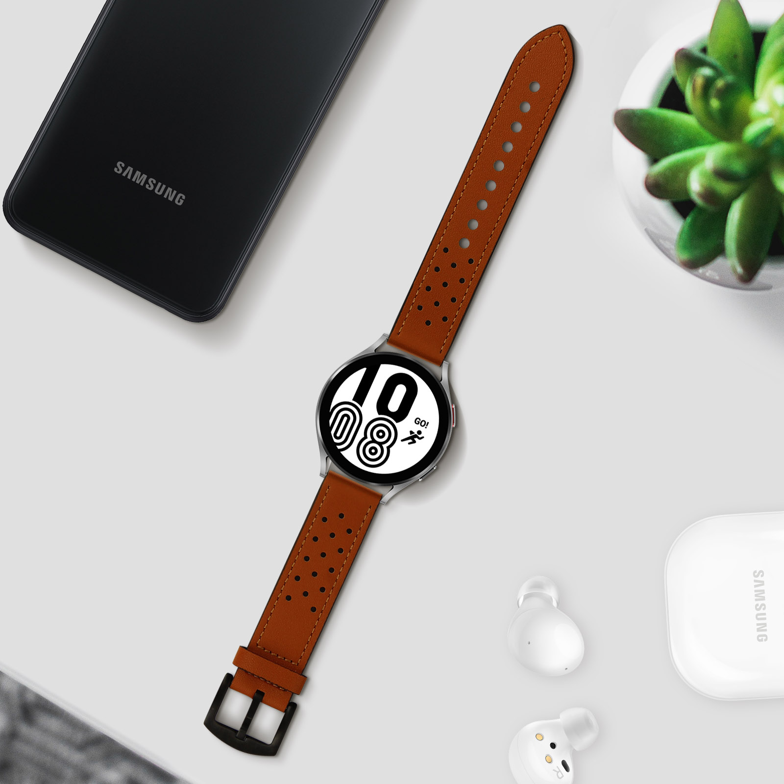 Uno smartwatch con cinturino in pelle marrone e altri accessori su un tavolo.