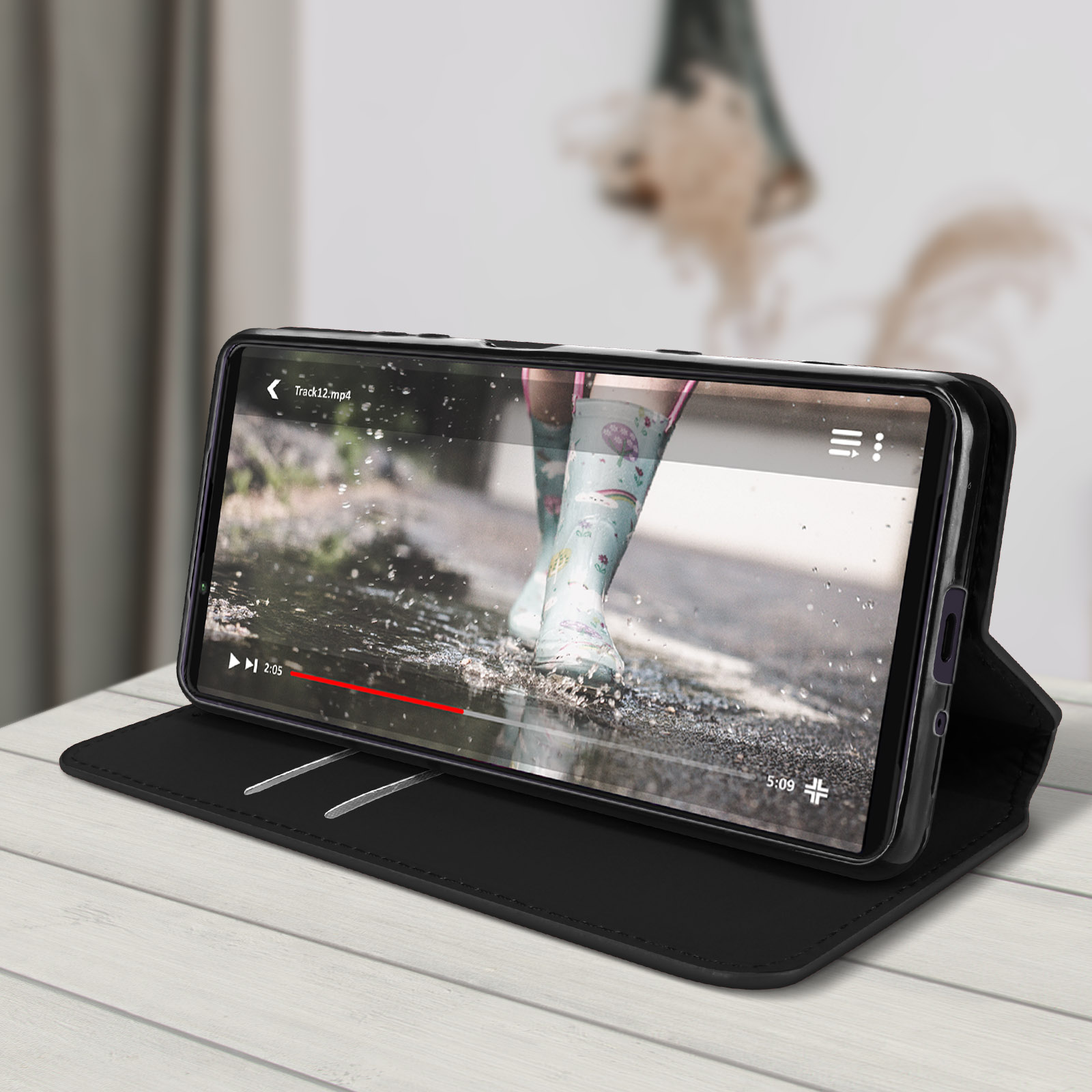Telefono in una custodia nera che mostra un video. Lo schermo mostra stivali nelle pozzanghere.