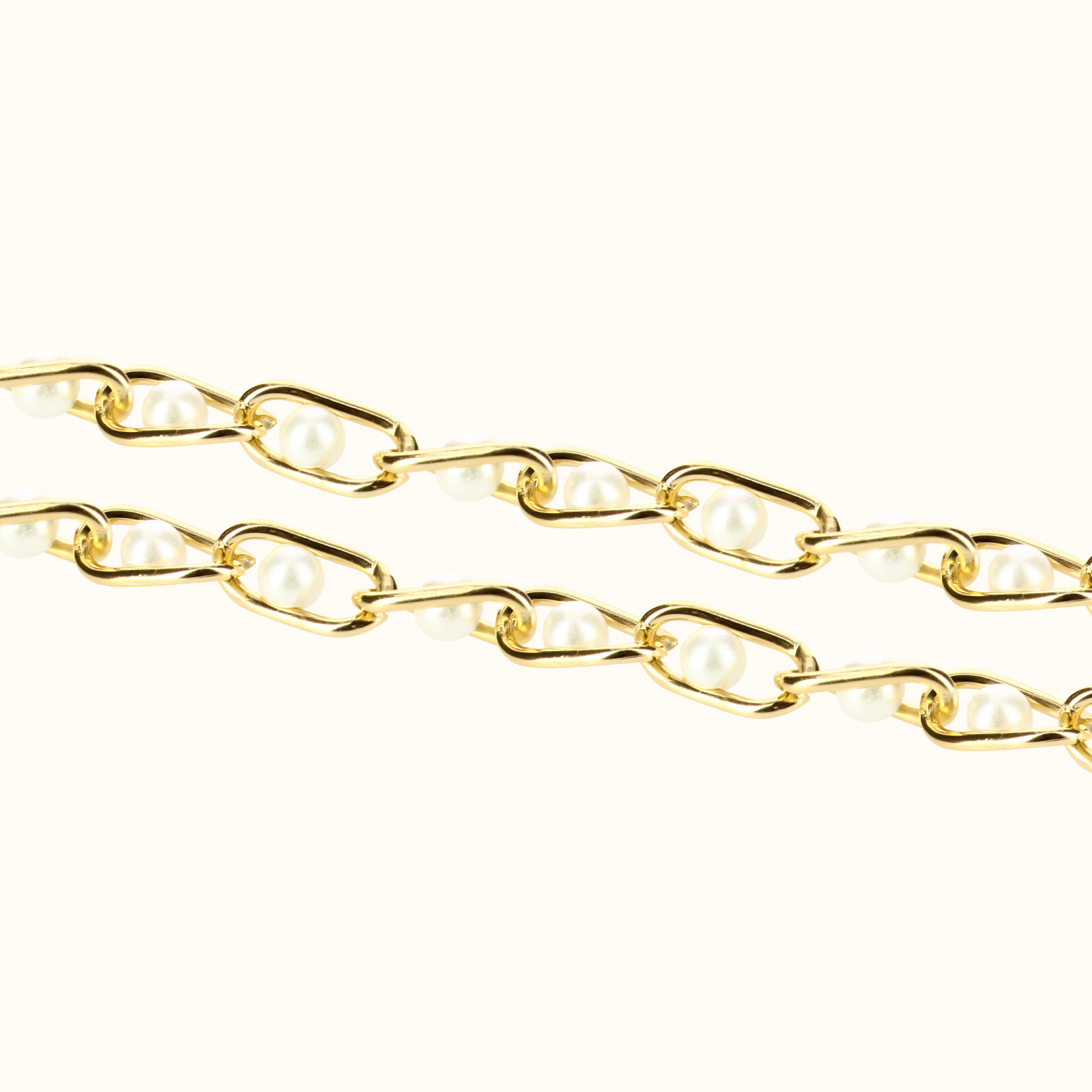 Due catene d'oro con perle su sfondo bianco.