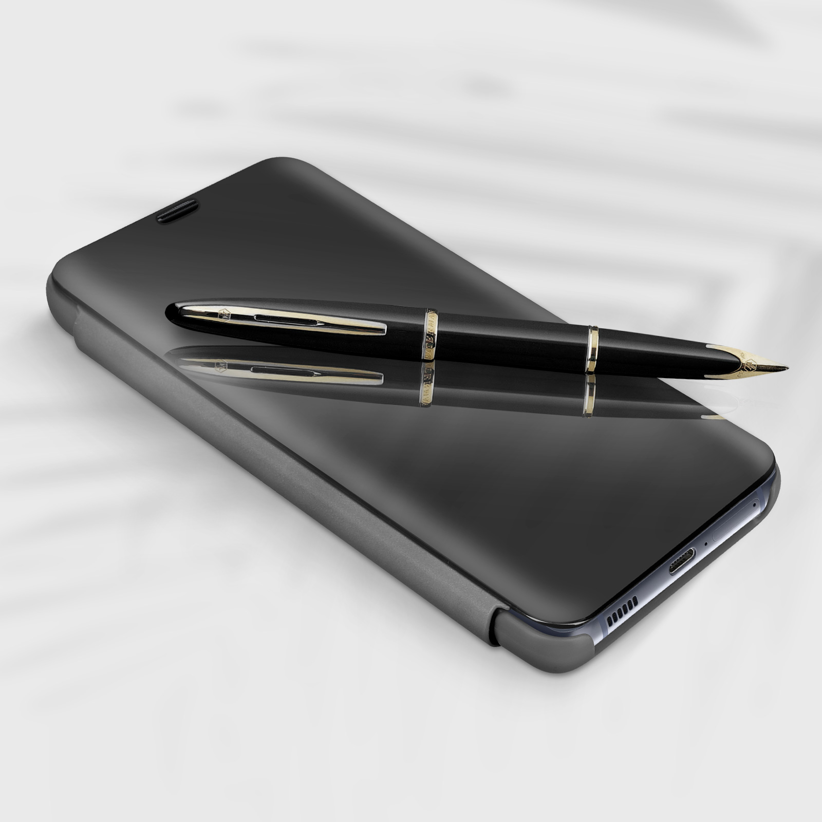 Una custodia nera per telefono con una penna sopra, un riflesso della penna.