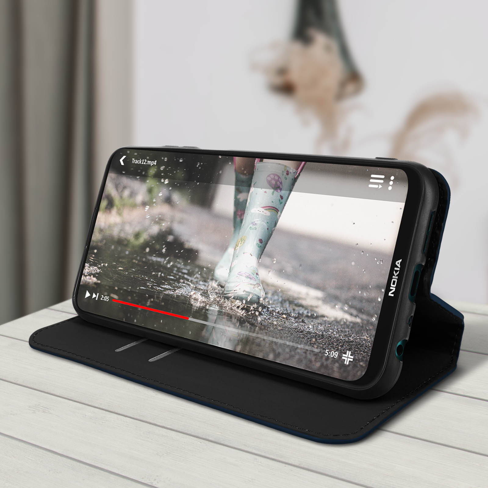 Telefono che mostra video di stivali da pioggia. Telefono aperto su custodia. Sfondo: tavolo, sfocato.