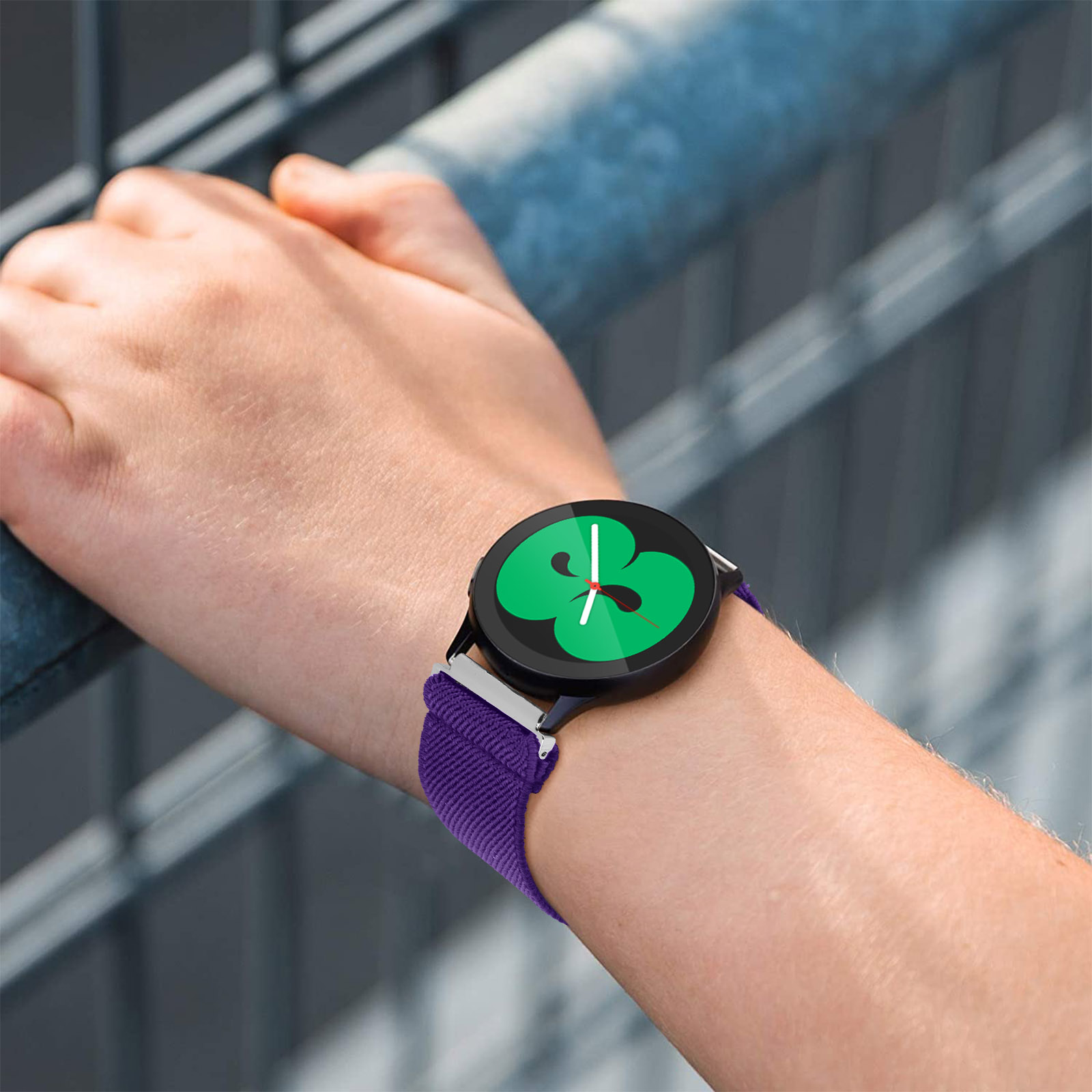 Polso con cinturino viola e smartwatch nero.