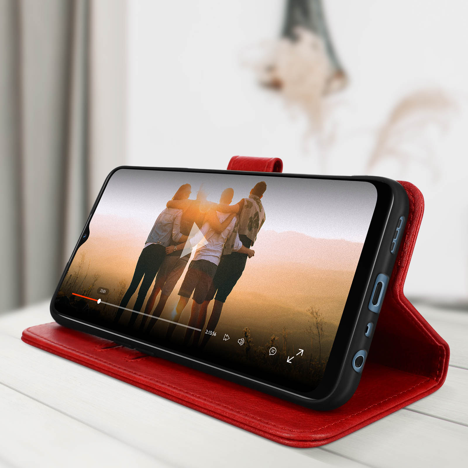 Telefoon in een rode hoes met een video van drie mensen die elkaar omhelzen bij zonsondergang.