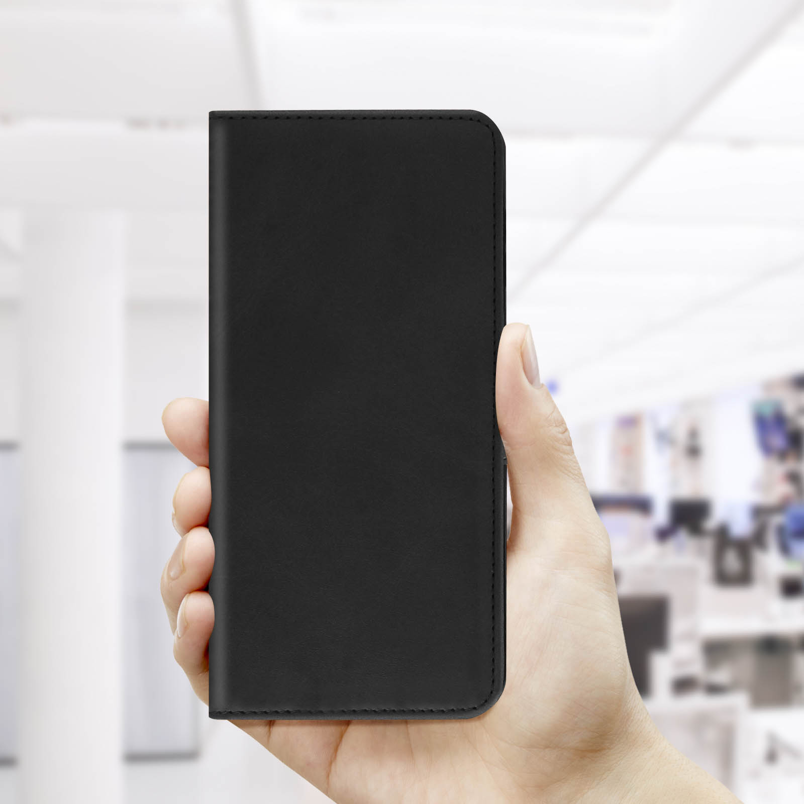 Main tenant un étui de téléphone noir. L'étui est fermé et rectangulaire.