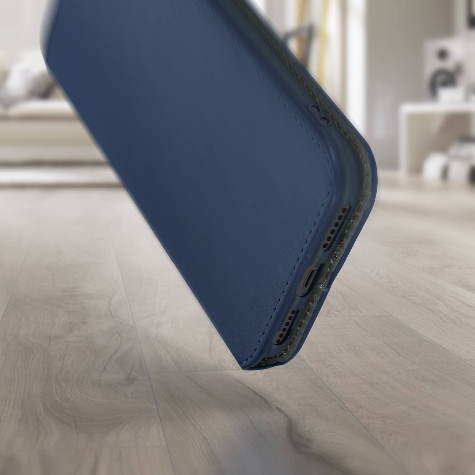 Gros plan d'un étui de téléphone bleu foncé, légèrement incliné, sur un plancher en bois.