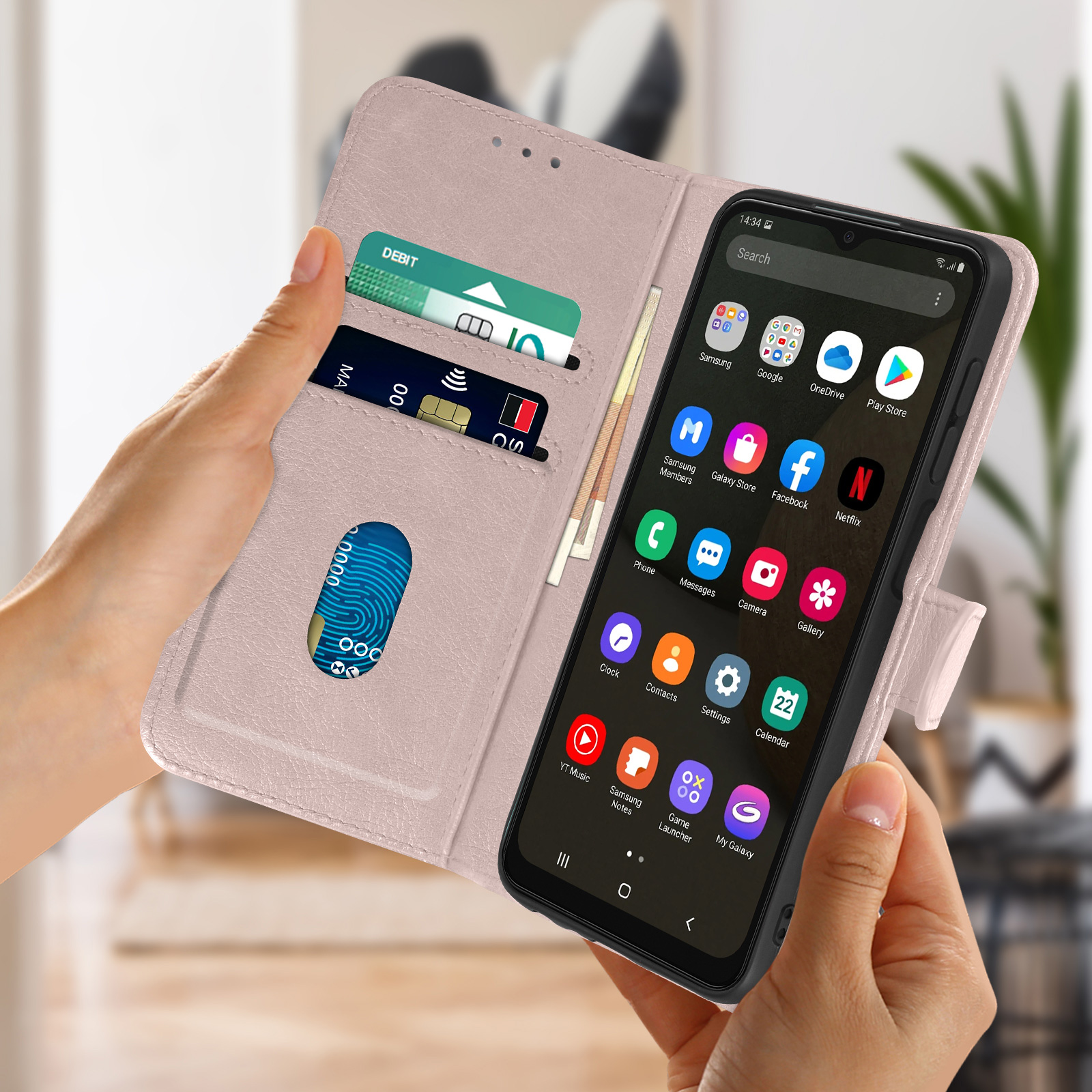Un téléphone dans un étui rose, tenu par des mains. L'écran affiche des applications. Le fond est flou.