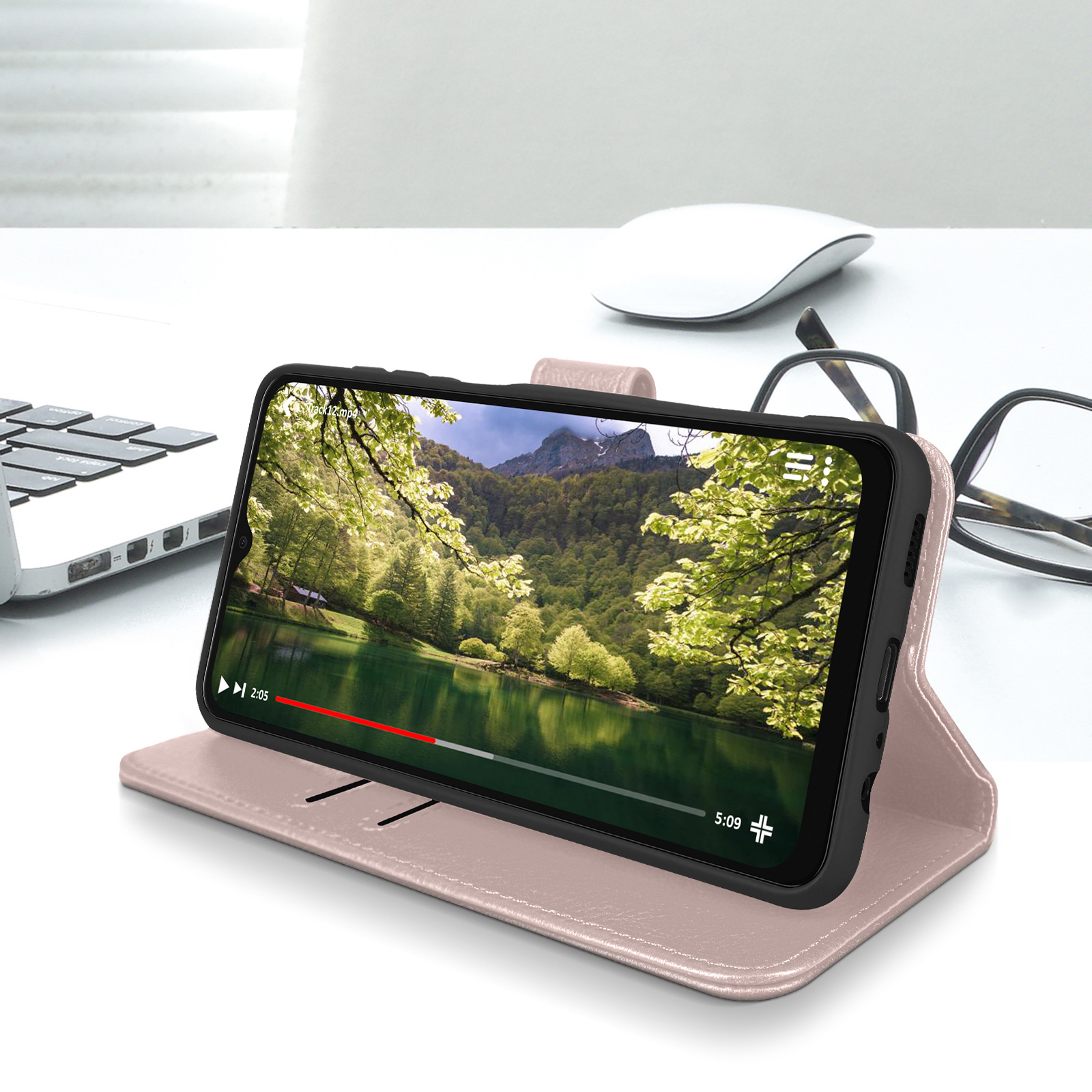 Un téléphone sur un support affiche une vidéo. Bureau blanc, ordinateur, souris et lunettes visibles en arrière-plan.