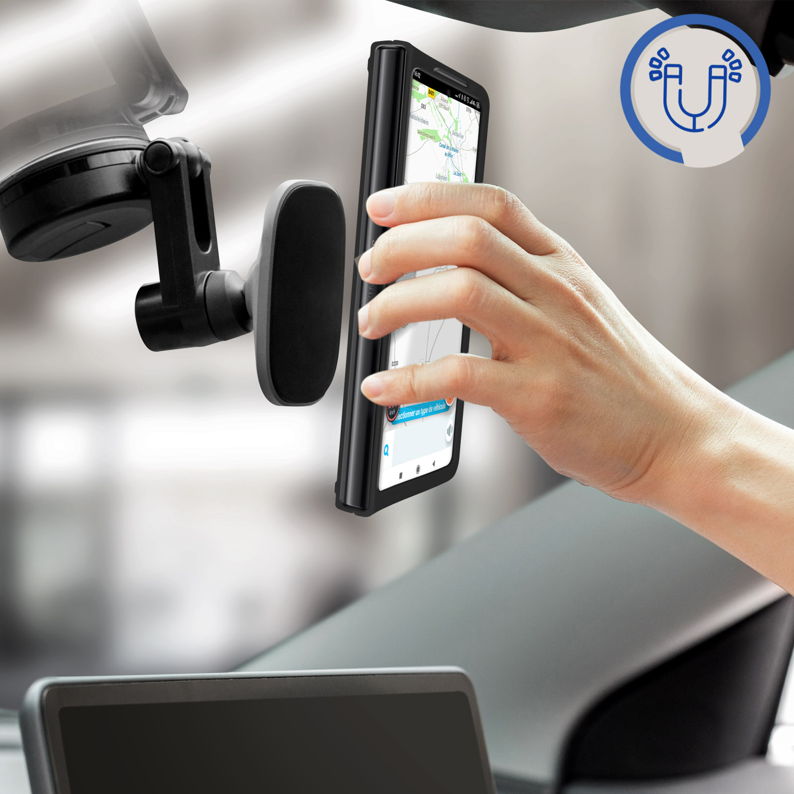 Téléphone monté sur pare-brise avec support magnétique. Une main atteint le téléphone.