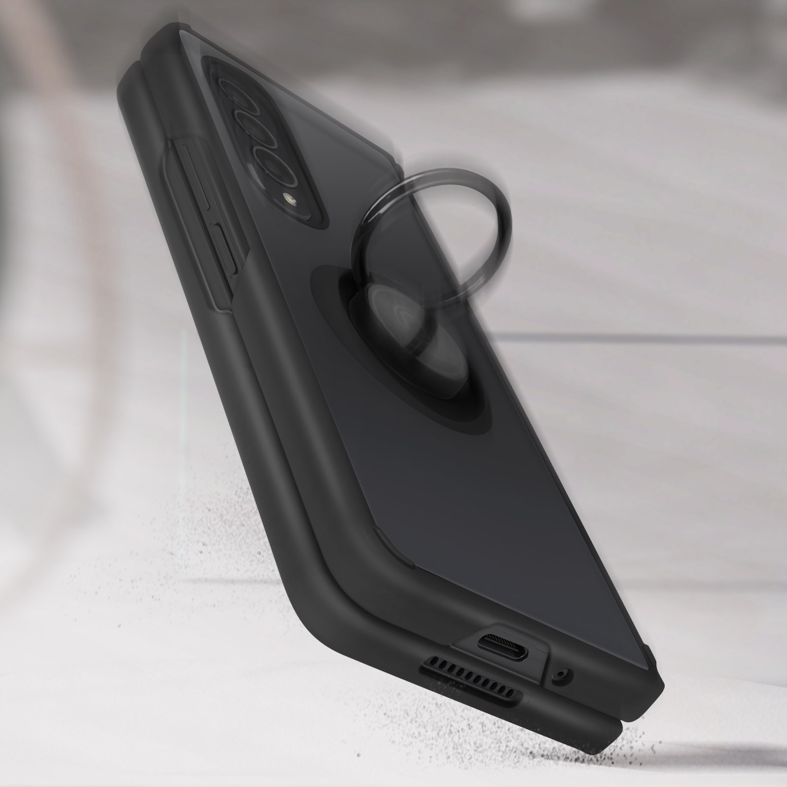 Coque de téléphone noire avec anneau. La coque est noire. Elle a un anneau. Elle tombe sur une surface blanche.