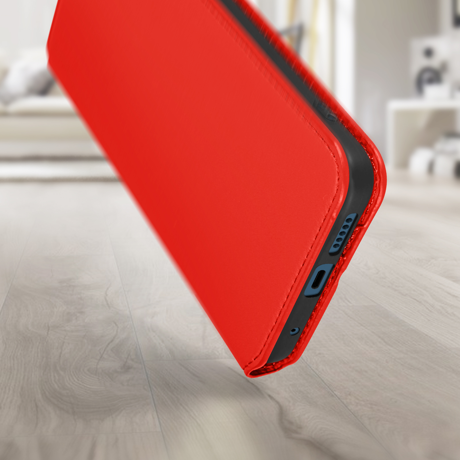 Étui de téléphone rouge, vue en angle. Montre le côté avec les ports et boutons. Sol en bois en arrière-plan.