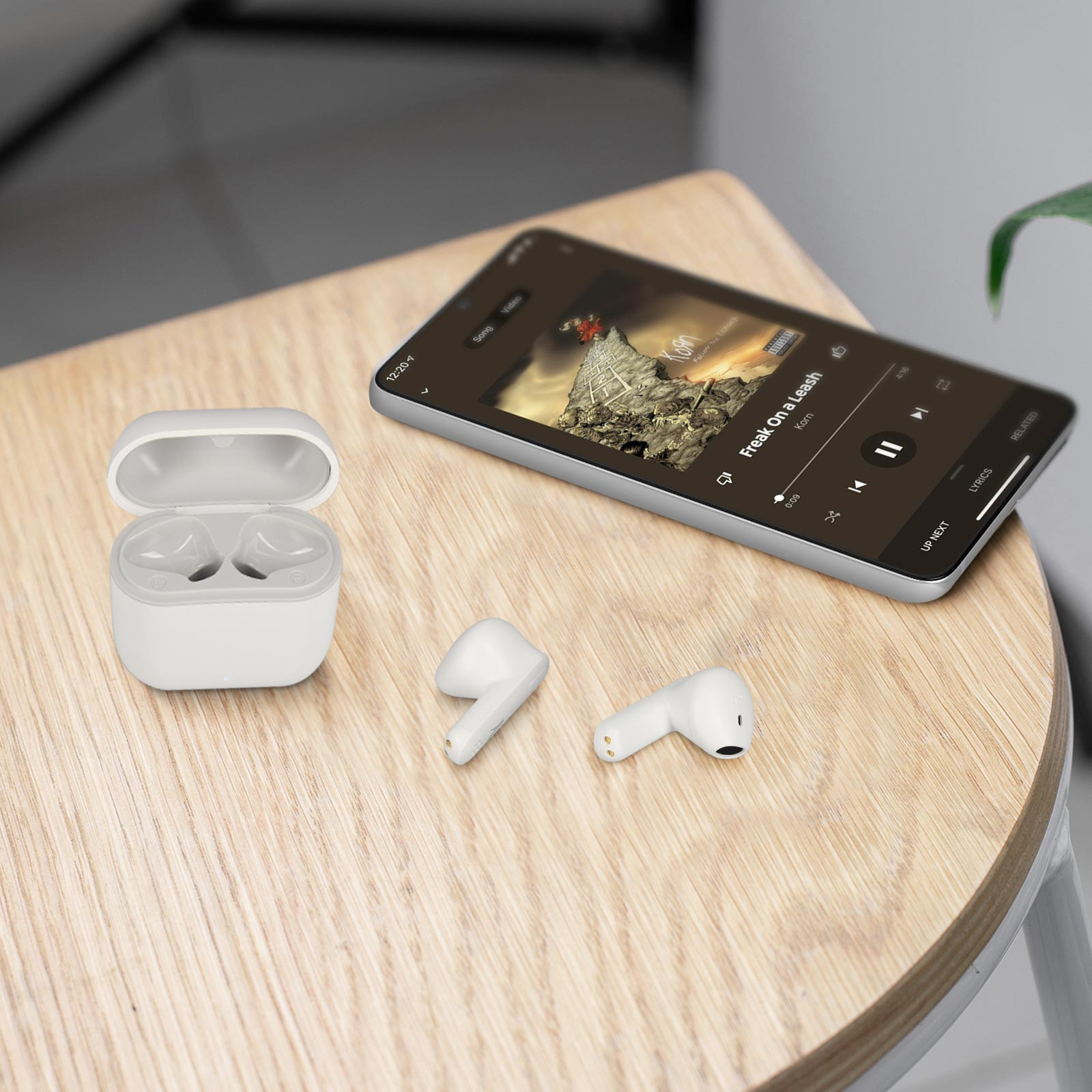 Auricolari in custodia di ricarica bianca. Il telefono mostra l'app musicale e una canzone.