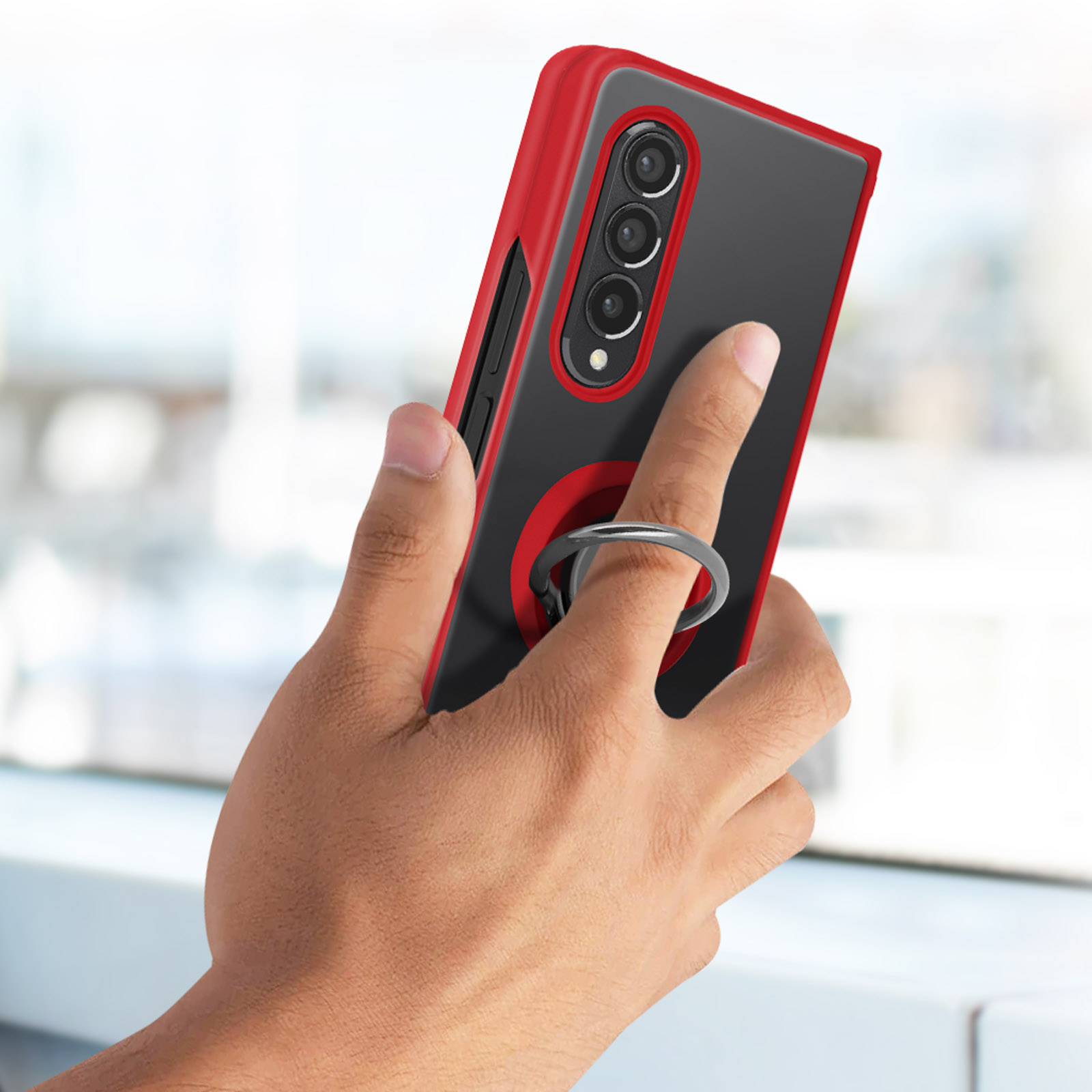 Main tenant une coque noire avec cadre rouge et anneau argenté.
