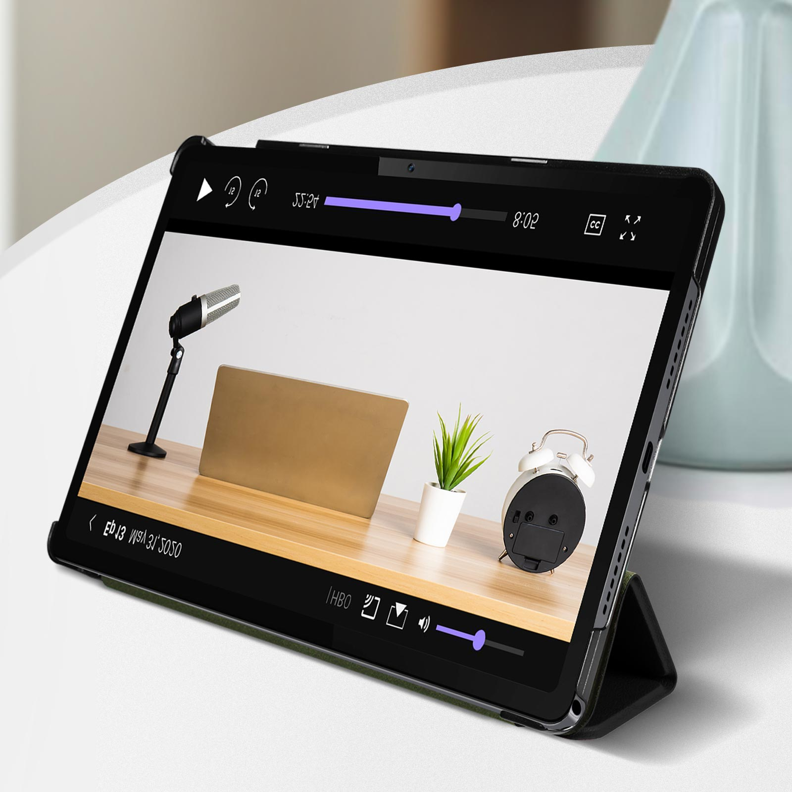 Tablet con video. Microfono, pianta e sveglia sul tavolo.