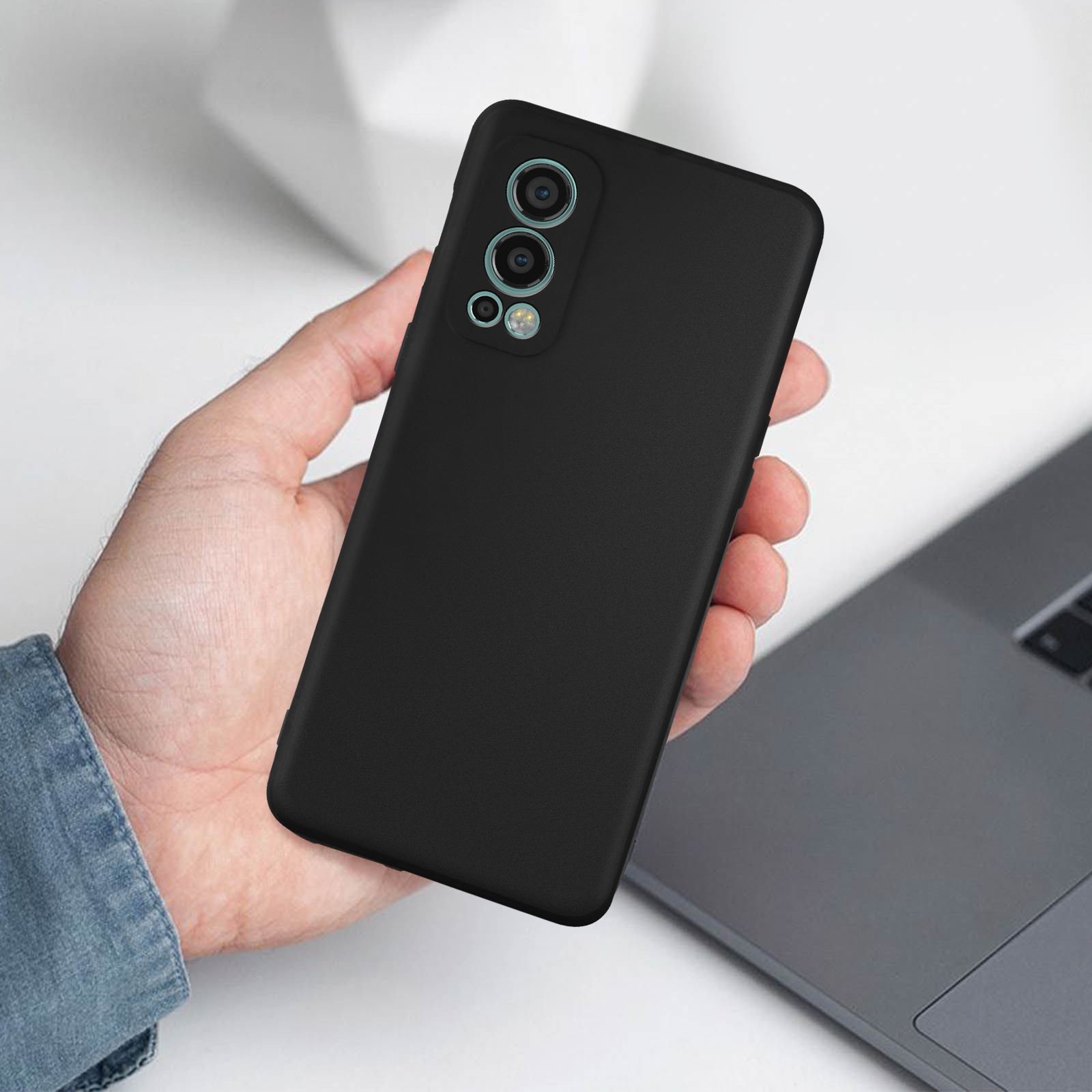 Mano che tiene una custodia nera per telefono. La custodia ha tre obiettivi. Un laptop sullo sfondo.