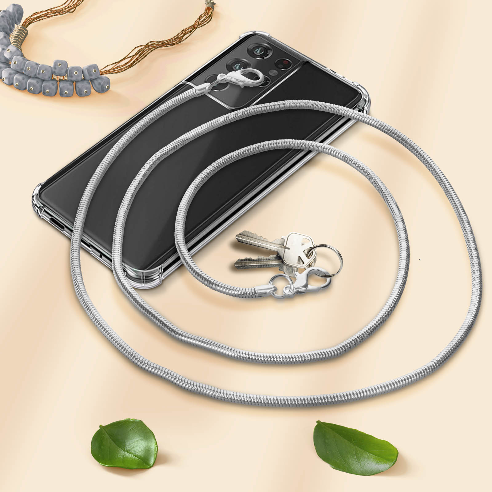 Uno smartphone in custodia trasparente con catena d'argento, chiavi e gioielli.